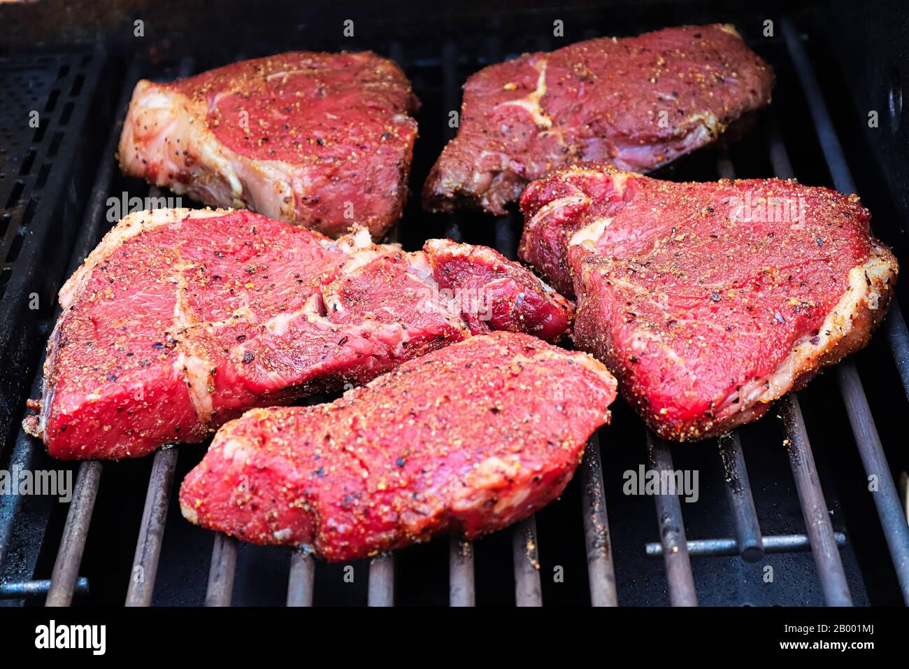 Rohe, gewürzte Steaks auf einem Grillgrill. Stockfoto