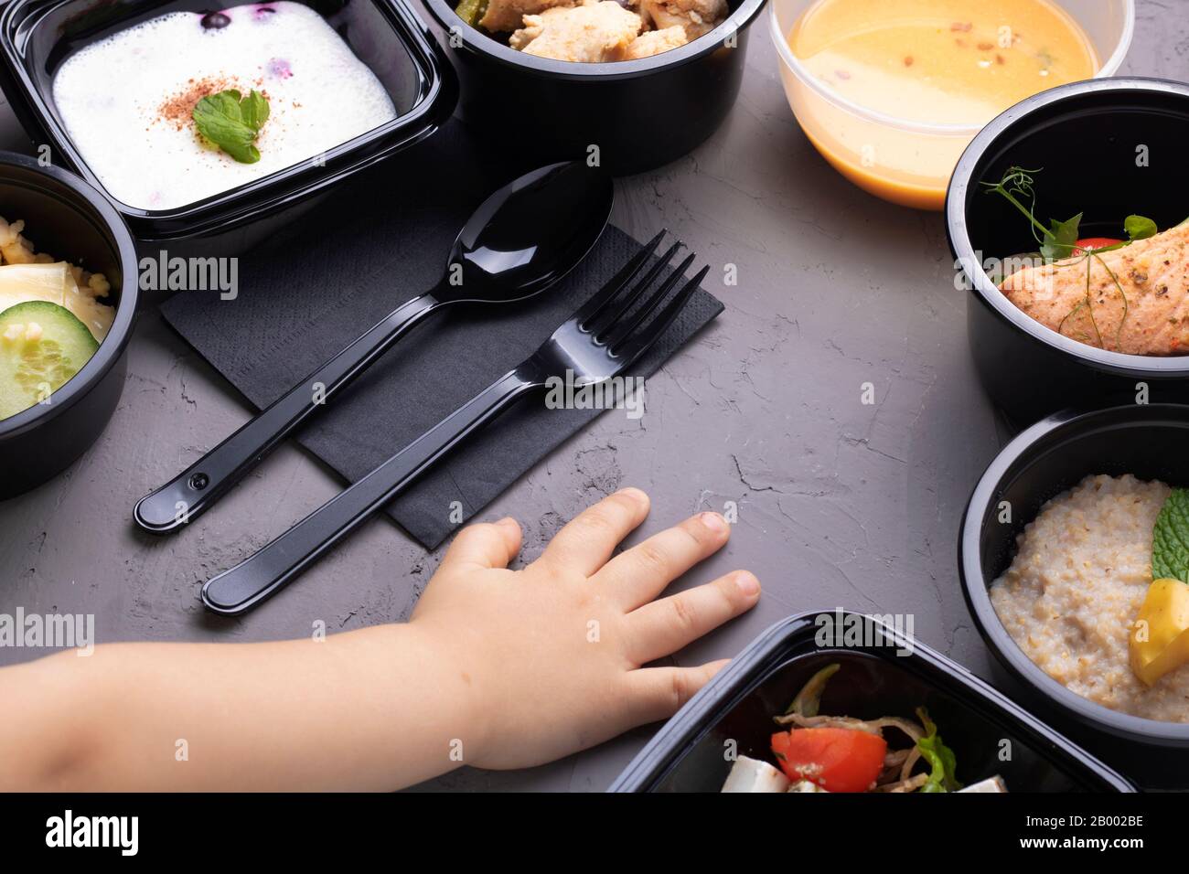 Kinder reichen in der Nähe von Kisten mit köstliches Essen, Lunchbox mit Reis, gemischtem Gemüse, gekochtem Ei, Nüssen und Kürbiscremesuppe, Draufsicht, flacher Lay Stockfoto