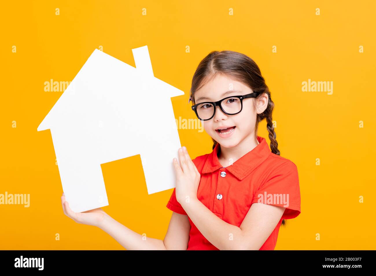 Glückliches kleines Mädchen, das Hausmodell zeigt und hält Stockfoto