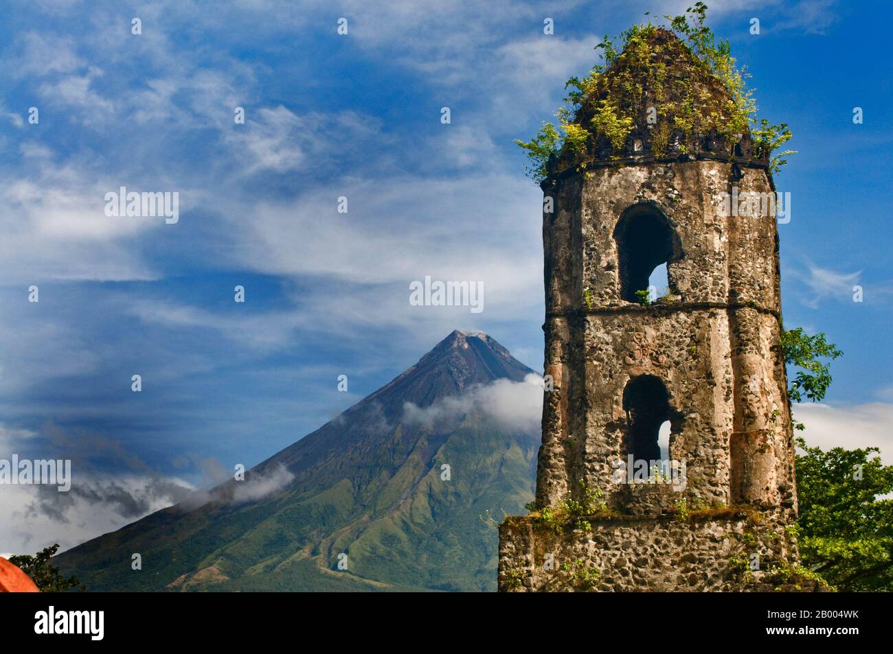 Der Vulkan Mayon, der für seinen perfekten Kegel bekannt ist, ist ein beliebtes Touristenziel. Die Ruinen von Cagsawa sind Reste einer franziskanischen Kirche aus dem 16. Jahrhundert. Stockfoto