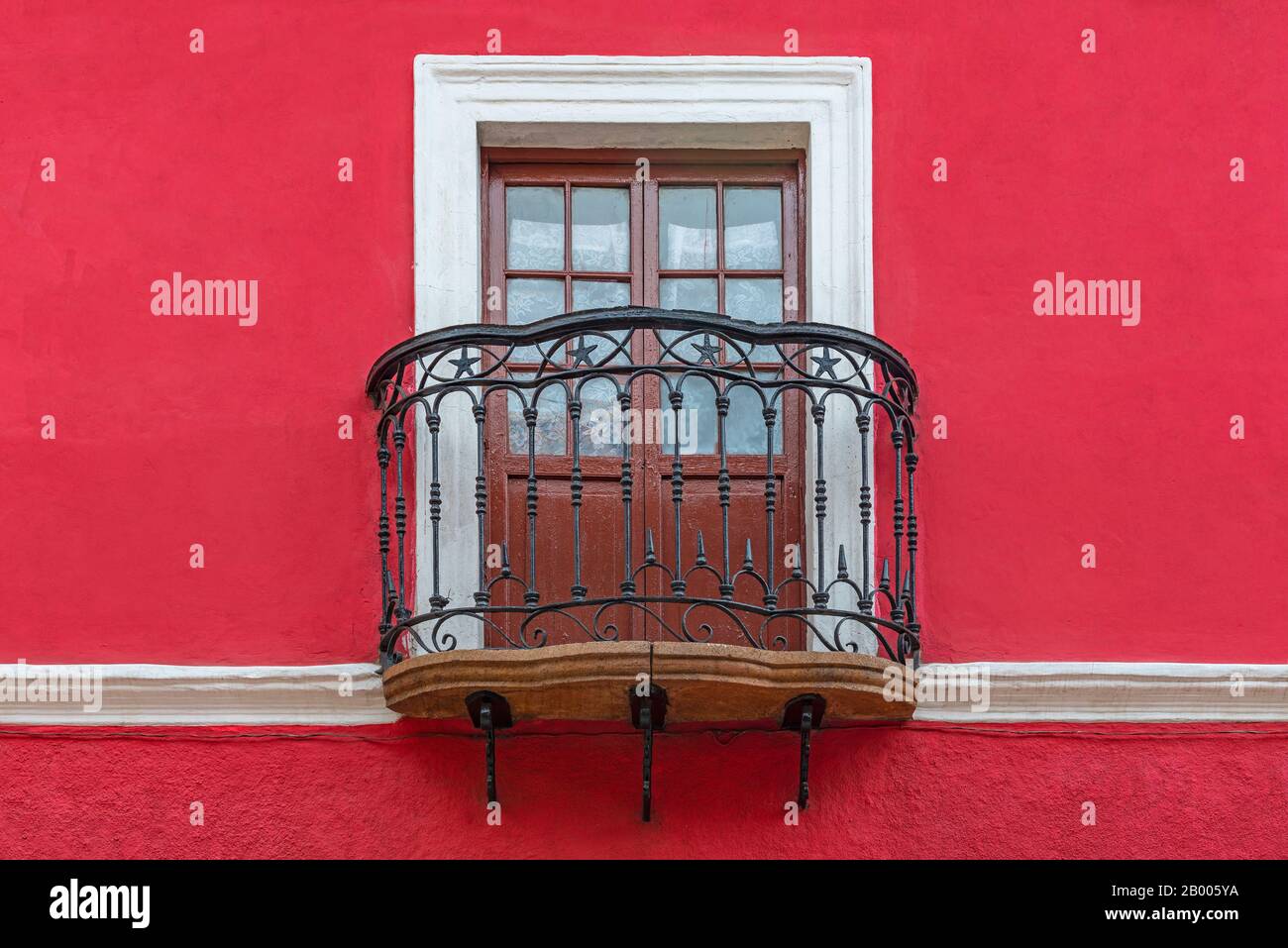 Balkon im Kolonialstil mit Holzfenster, schmiedeeisernen Dekorationen und roter Fassade, Potosi, Bolivien. Stockfoto