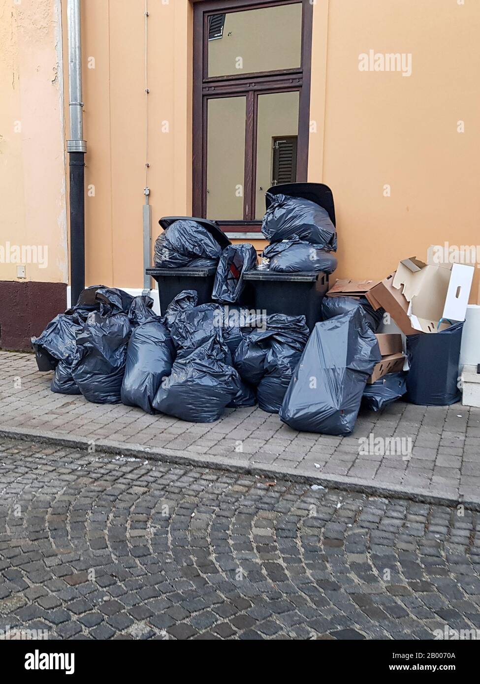 Ein Haufen sortierter Müll auf der Straße. Im Müll befinden sich schwarze Taschen, Mülltonnen und Pappe. Für die Abfallsammlung vorbereitet. Stockfoto