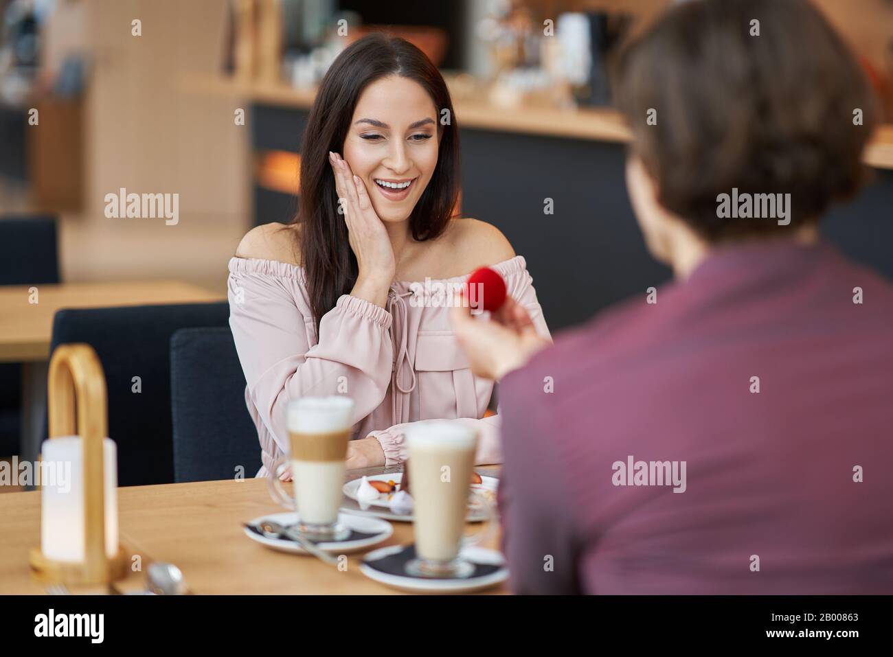 Junger Mann, der seiner Freundin in einem Café vorschlägt Stockfoto