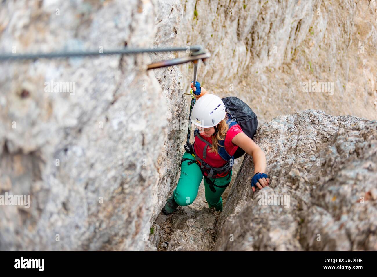 Junge Frau, Wanderer, die auf einem Klettersteig klettern, der auf einem Stahlseil zwischen Felsen, Über den Klettersteig Francesco Berti, Sorapiss-Rundkurs, in den Bergen befestigt ist Stockfoto
