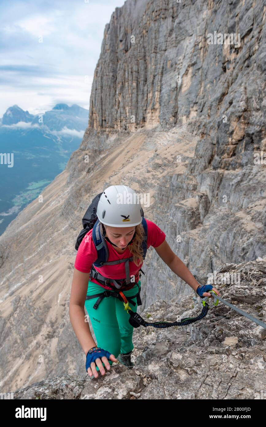 Junge Frau, mit Stahlseil gesicherter Wanderer beim Klettern auf der Felswand, Über Ferrata Francesco Berti, Sorapiss-Rundkurs, in den Bergen, Belluno, Italien Stockfoto