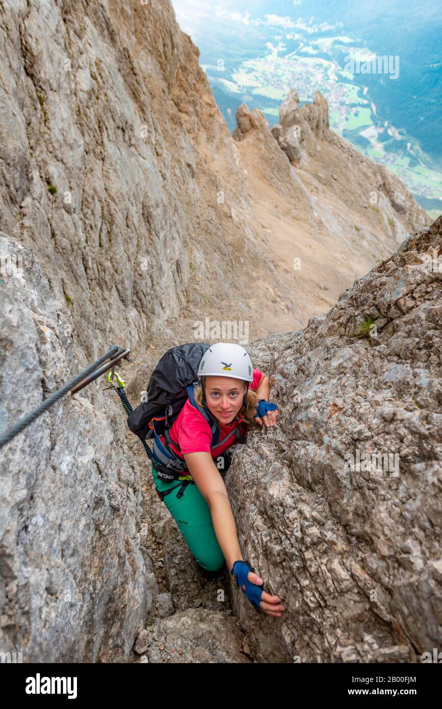 Junge Frau, Wanderer, die auf einem Klettersteig klettern, der auf einem Stahlseil zwischen Felsen, Über den Klettersteig Francesco Berti, Sorapiss-Rundkurs, in den Bergen befestigt ist Stockfoto