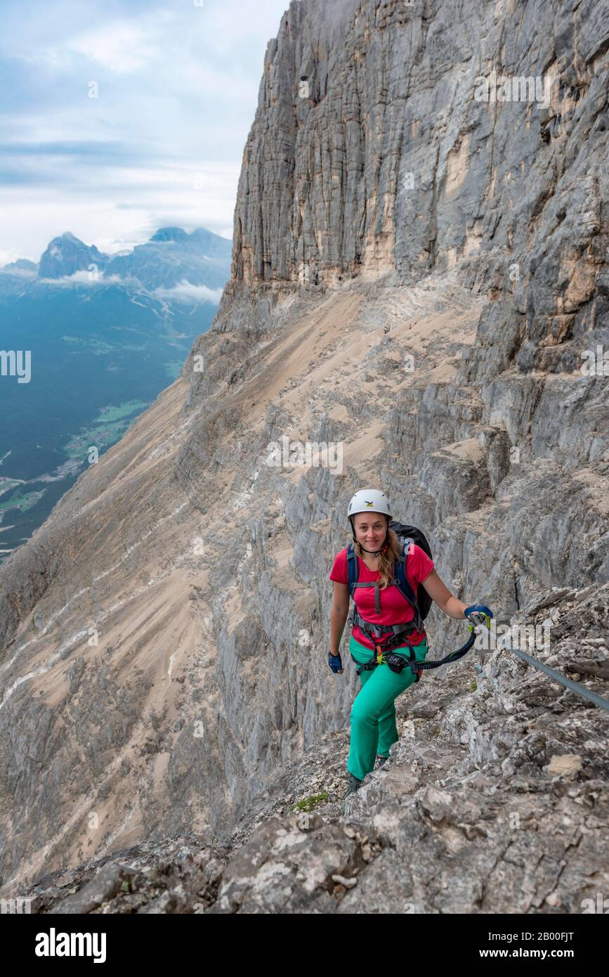 Junge Frau, mit Stahlseil gesicherter Wanderer beim Klettern auf der Felswand, Über Ferrata Francesco Berti, Sorapiss-Rundkurs, in den Bergen, Belluno, Italien Stockfoto