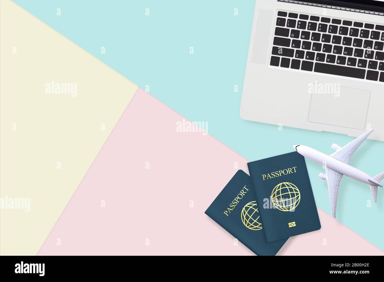 Flacher Reisepass, weißes Flugzeugmodell und Computerlaptop auf pastellblauem, gelbem und pinkfarbenem Hintergrund mit Kopienfläche. Reisen, Visum und Urlaub Stockfoto