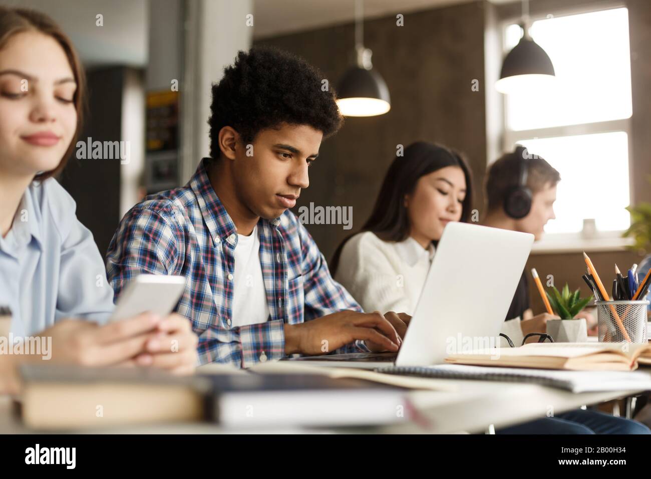 College-Gruppenmitglieder, die in der Bibliothek studieren, Kerl mit Laptop Stockfoto