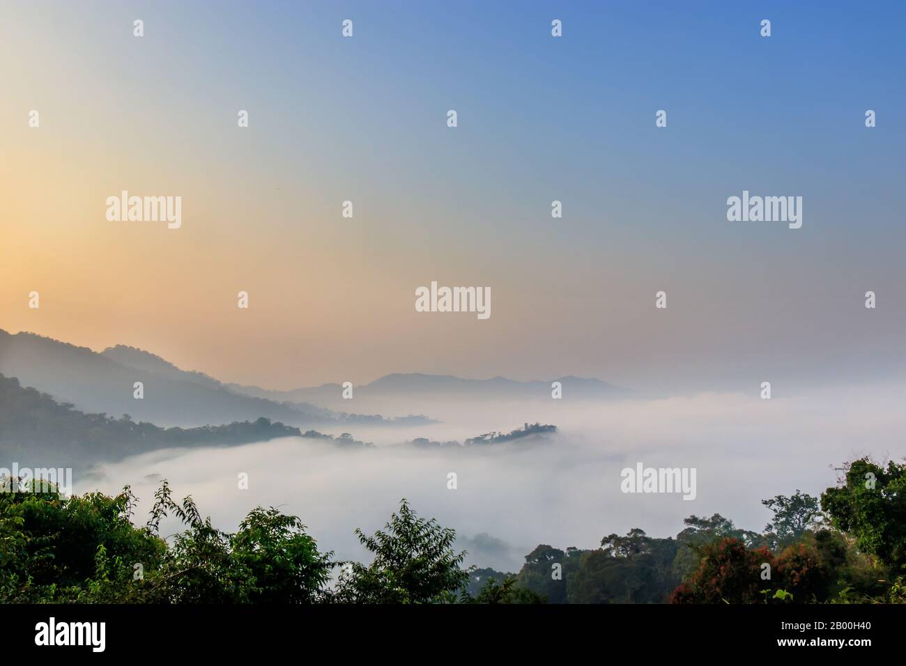 Schöner Blick auf die Landschaft auf dem Berggipfel mit Nebel am Morgen mit orangefarbenem Sonnenaufgang. Landschaftshintergrund Stockfoto