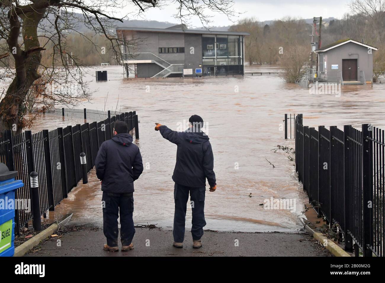 Zwei Männer sehen in der Folge von Storm Dennis einen überfluteten Bereich des Sportpavillons an der Monmouth School, Monmouth. Stockfoto