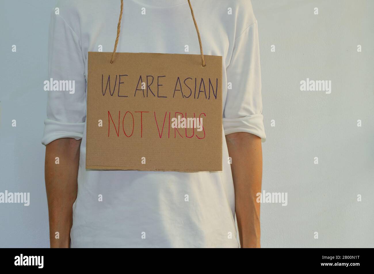 Ein asiatisches Schild mit hängenden Pappkartons enthält eine Handschrifterkennung, die liest, DASS WIR ASIATISCH sind, NICHT VIRUS, Antirassismuskonzept Stockfoto