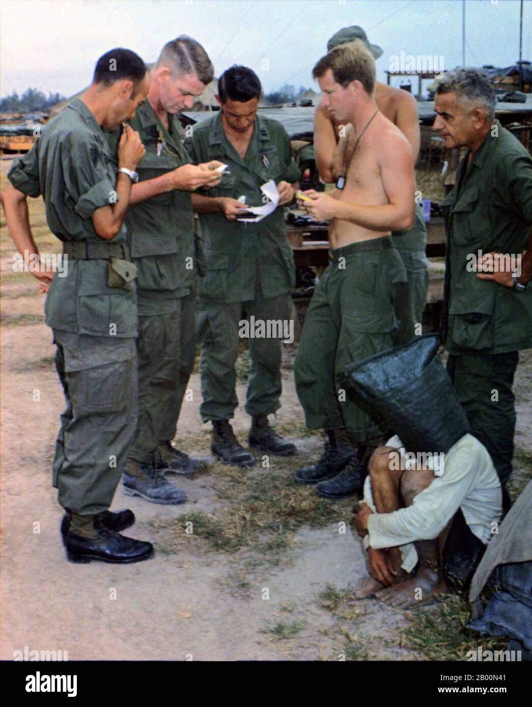 Vietnam: Ein Verdächtiger des NLF (Viet Cong), der 1968 bei einem Angriff auf einen amerikanischen Außenposten nahe der kambodschanischen Grenze in Südvietnam gefangen genommen wurde, wird verhört. Die Vietcong (vietnamesisch: Việt cộng), oder National Liberation Front (NLF), war eine politische Organisation und Armee in Süd-Vietnam und Kambodscha, die die Vereinigten Staaten und Süd-vietnamesischen Regierungen während des Vietnamkrieges (1955-1975) bekämpft. Sie hatte sowohl Guerilla- als auch reguläre Armeeeinheiten, sowie ein Netzwerk von Kadern, die Bauern auf dem von ihr kontrollierten Gebiet organisierten. Viele Soldaten wurden in Südvietnam rekrutiert. Stockfoto