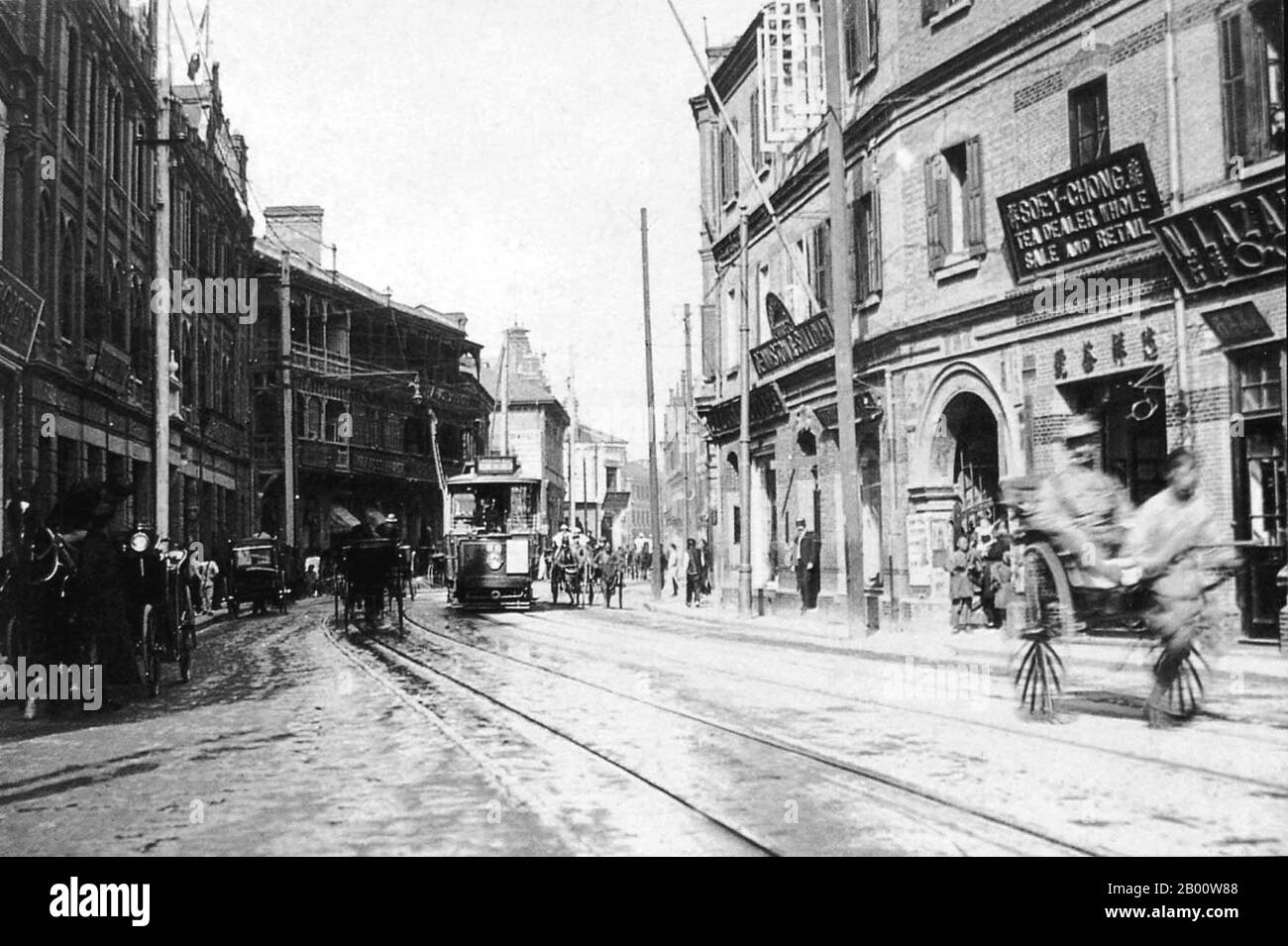 China: Shanghais Nanjing Road mit Straßenbahn, Rikscha und Geschäften ca. 1910. Die internationale Aufmerksamkeit für Shanghai wuchs im 19. Jahrhundert aufgrund seines wirtschaftlichen und handelspolitischen Potenzials am Jangtse-Fluss. Während des Ersten Opiumkrieges (1839–1842) hielten britische Truppen die Stadt vorübergehend. Der Krieg endete mit dem Vertrag von Nanjing von 1842, der Shanghai und andere Häfen für den internationalen Handel öffnete. Im Jahr 1863 schlossen sich die britische Siedlung, die südlich des Suzhou-Baches (Huangpu-Bezirk) liegt, und die amerikanische Siedlung, nördlich des Suzhou-Baches (Hongkou-Bezirk), zusammen, um die internationale Siedlung zu bilden Stockfoto
