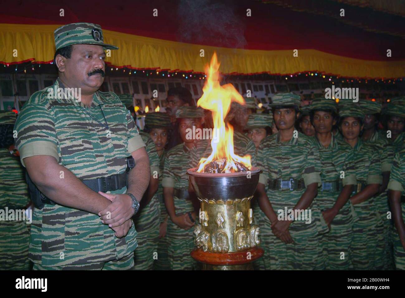 Sri Lanka: Befreiungstiger von Tamil Eelam (LTTE) Führer Velupillai Prabhakaran vor einer flammenden Urne bei einer Zeremonie mit weiblichen LTTE Truppen, c. 2006. Der Bürgerkrieg in Sri Lanka begann am 23. Juli 1983 und entwickelte sich schnell zu einem ständigen Aufstand gegen die Regierung Colombo durch die Befreiungstiger von Tamil Eelam (LTTE), allgemein bekannt als die Tamil Tigers, und andere wenige Rebellengruppen, Die im Norden und Osten der Insel für die Schaffung eines unabhängigen tamilischen Staates namens Tamil Eelam kämpften. Nach einem 26-jährigen Militärfeldzug besiegte das srilankische Militär die LTTE im Mai 2009. Stockfoto