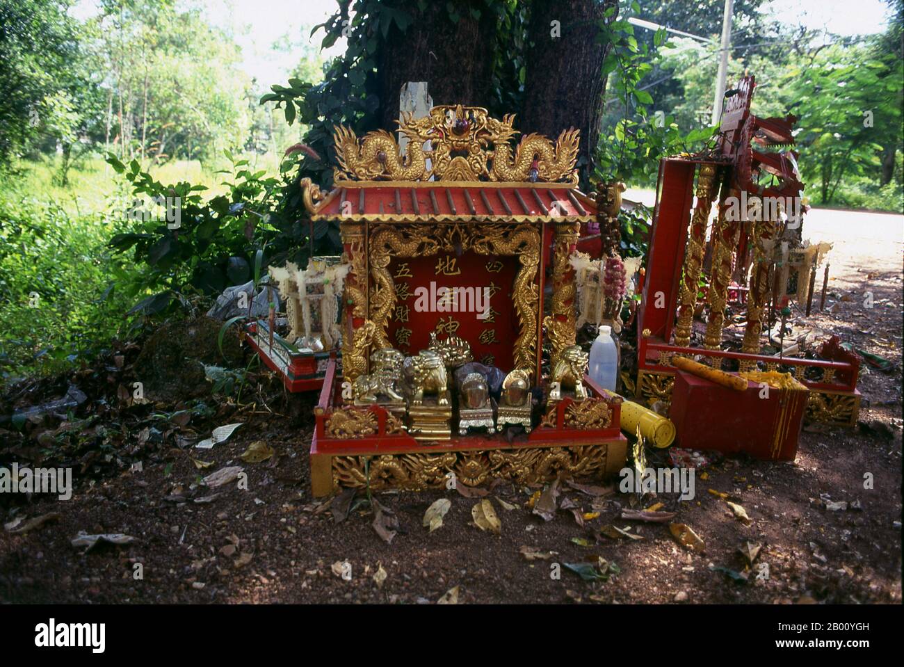 Thailand: Chinesische Geisterhäuser und Ahnen-Schreine um einen Baum in der Nähe des Kamphaeng Phet lak mueang oder Stadtpfosten, Kamphaeng Phet Historical Park. Ein Geisthaus ist ein Schrein zum Schutzgeist eines Ortes. Sie sind in der Regel in den südostasiatischen Ländern Burma, Kambodscha, Laos und Thailand zu finden. Die meisten Häuser und Geschäfte haben ein Geisterhaus, das an einem glückverheißenden Ort, meistens in einer Ecke des Grundstücks, aufgestellt wird. Der Ort kann nach Rücksprache mit einem Brahmanen Priester gewählt werden. Das Geisterhaus ist normalerweise in Form eines Miniaturhauses oder Tempels, der auf einer Säule montiert ist. Stockfoto