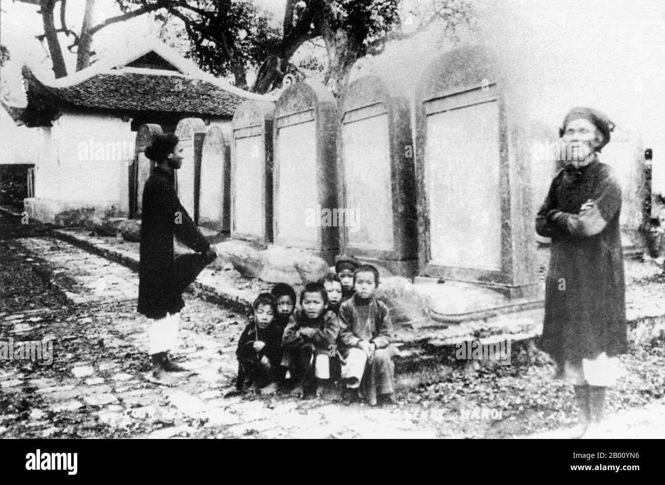 Vietnam: Kinder hocken vor den Steinstelen im Literaturtempel in Hanoi (Anfang 20th. Jahrhundert) auf ein Foto. Obwohl es in Vietnam viele "Tempel der Literatur" (Van Mieu) gibt, ist dieser in Hanoi mit Abstand der bekannteste. Es wurde 1070 als konfuzianischer Tempel gegründet und wurde 1076 die erste Universität des Landes. Kaiser Le Thanh Tong begründete die Tradition, die auf das Jahr 1484 zurückgeht, die Namen der Preisträger der Universität auf steinernen Stelen zu schnitzeln, die auf steinernen Schildkröten platziert wurden. Stockfoto