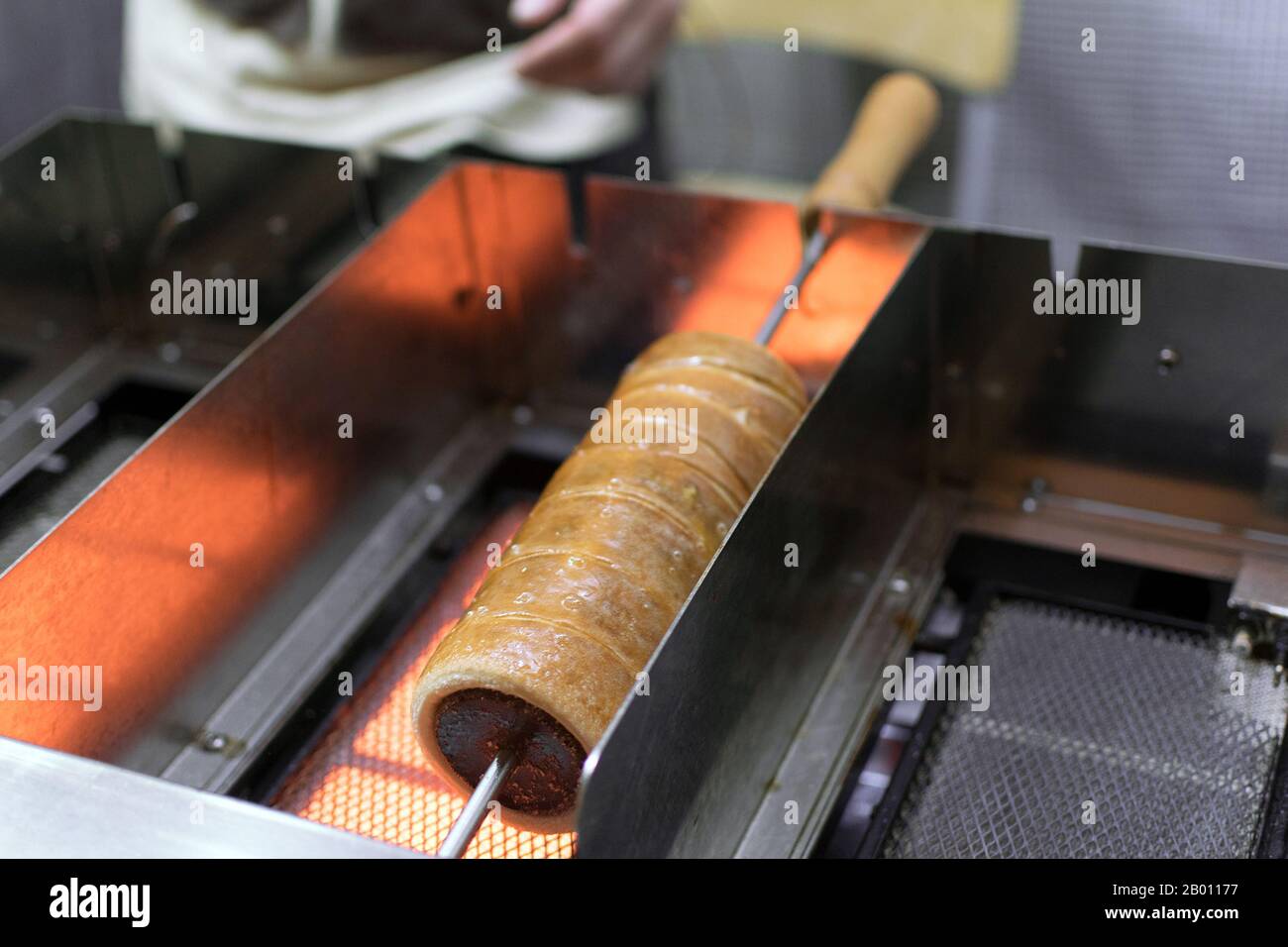 Zubereitung des traditionellen Trdelnik eine Art Spitkuchen aus gerolltem Teig, der um einen Stock gewickelt und gegrillt wird. Stockfoto