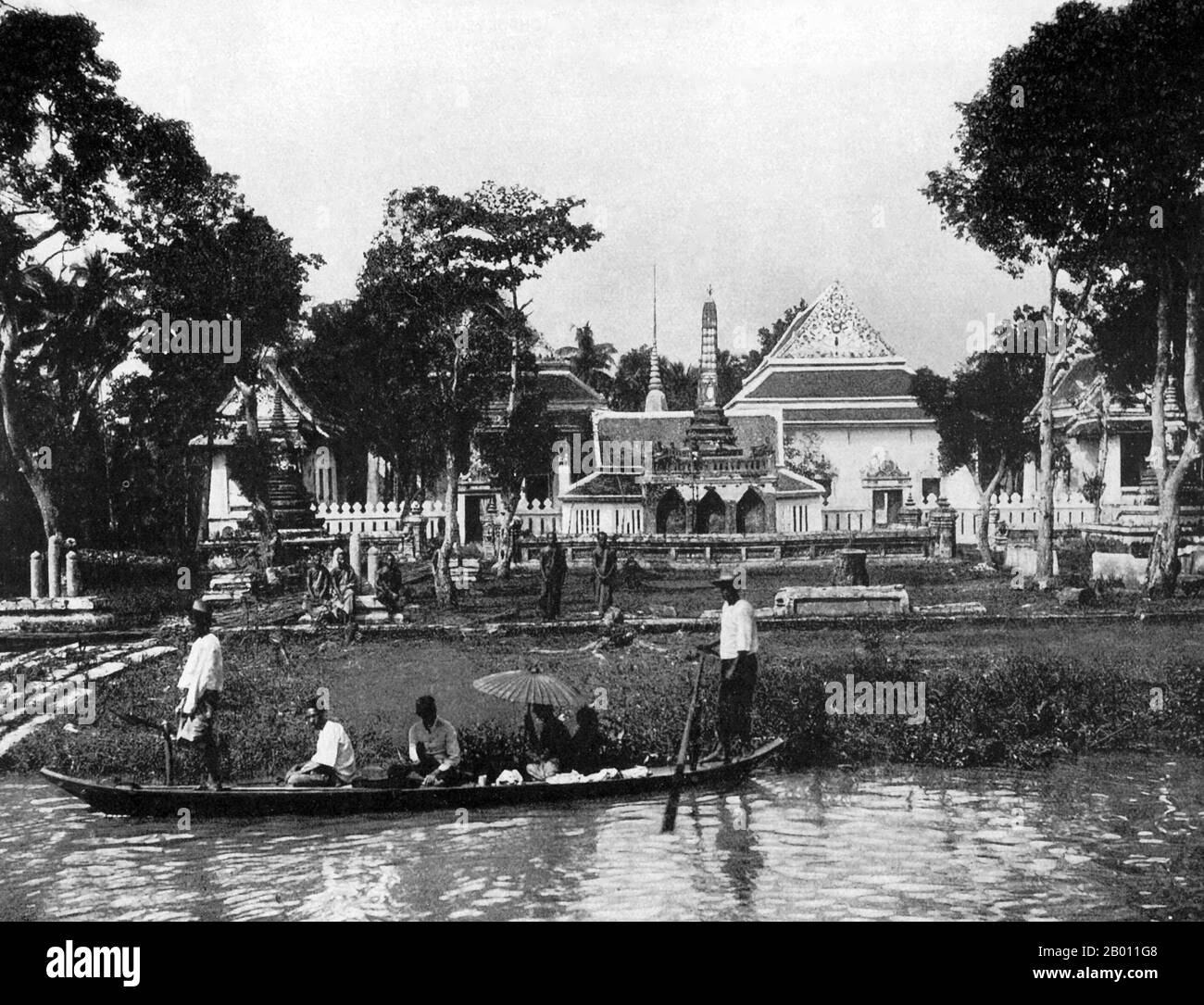 Thailand: Ein kleines Passagierboot vor einem buddhistischen Tempel in der Nähe von Bangkok, c. 1900. Um die Wende des 20. Jahrhunderts waren die meisten Siamesen Reisbauern, die entlang der Wasserwege lebten und arbeiteten. Jeder Haushalt hatte ein Boot, von dem schätzungsweise 600,000 die Kanäle und Flüsse von Bangkok befuhren. Rudern wurde von der Rückseite des Bootes aus durchgeführt. Die meisten Häuser wurden aus Holz und Bambus gebaut und auf Stelzen mit einer Leiter zum Wasser gebaut. Stockfoto
