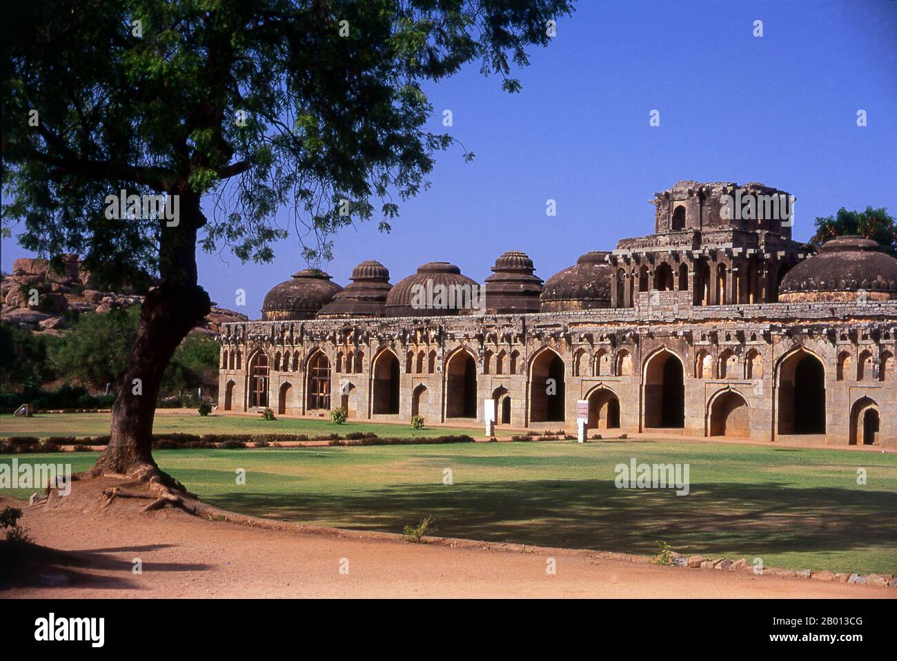 Indien: Elefantenställe, Hampi, Bundesstaat Karnataka. Die Elefantenställe wurden verwendet, um die zeremoniellen Elefanten des königlichen Haushalts zu beherbergen. Die Struktur zeigt einen deutlichen islamischen Einfluss in ihren Kuppeln und gewölbten Toren. Hampi ist ein Dorf im nördlichen Bundesstaat Karnataka. Es befindet sich in den Ruinen von Vijayanagara, der ehemaligen Hauptstadt des Vijayanagara-Reiches. Vor der Stadt Vijayanagara ist es weiterhin ein wichtiges religiöses Zentrum, in dem der Virupaksha-Tempel sowie mehrere andere Denkmäler der Altstadt untergebracht sind. Stockfoto