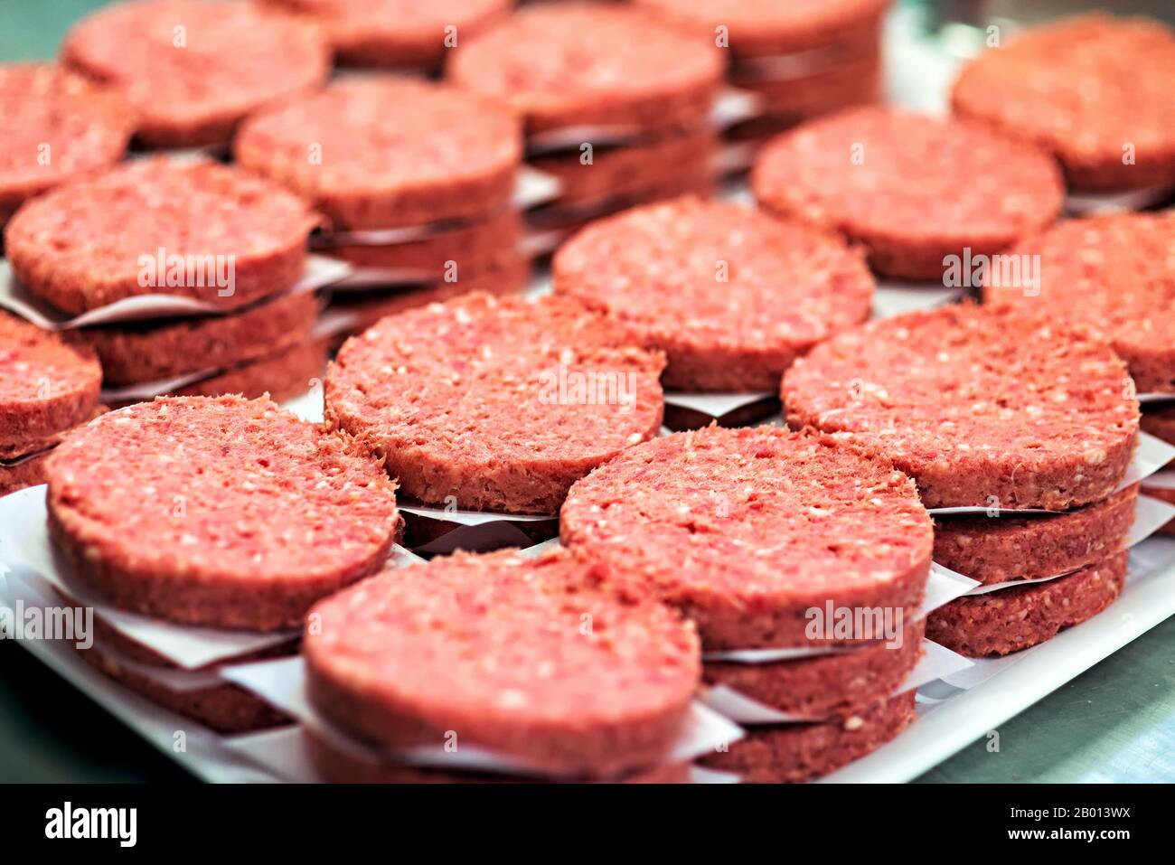Frische Hamburger rote Fleischscheibe stapelt sich in Nahaufnahme. Fast Food-Zutaten zum Kochen bereit Stockfoto