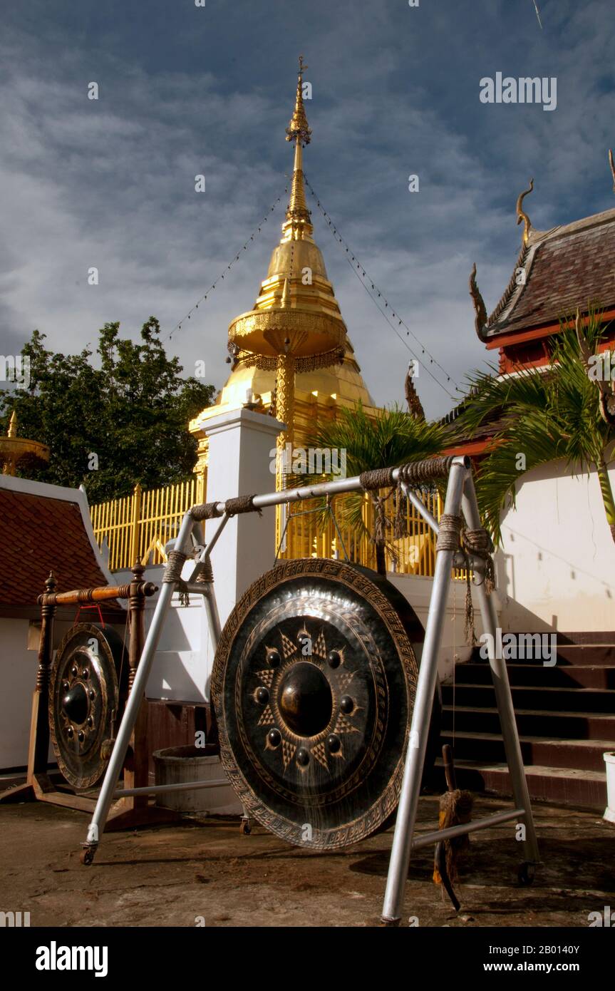 Thailand: Chedi und riesengong, Wat Phrathat Doi Kham, Chiang Mai. Wat Phrathat Doi Kham oder ‘Tempel des Goldenen Berges’, befindet sich in Tambon Mae Hia, etwa 10 km südlich der Altstadt von Chiang Mai, im schutze von Doi Suthep. Tempelrekorde behaupten, dass der Tempel über 1,300 Jahre ‘bis 687 u.Z.’ zurückreicht, während der Zeit vor LAN Na, als die Region von der einheimischen Animstin Lawa bewohnt wurde. Chiang Mai (was „neue Stadt“ bedeutet), manchmal auch als „Chiengmai“ oder „Chiangmai“ geschrieben, ist die größte und kulturell bedeutsamste Stadt im Norden Thailands. König Mengrai gründete die Stadt Chiang Mai im Jahr 1296. Stockfoto