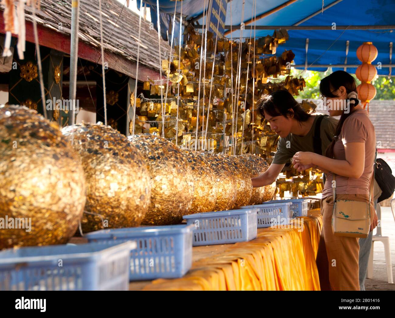 Thailand: Eine eifrige Frau und luk nimit (heilige Steinkugeln), Wat Phrathat Doi Kham, Chiang Mai. Luk nimit sind Steinkugeln, die an den vier Ecken und an den vier Kardinalpunkten eines neuen Ukossots zum Vergraben verwendet werden, ein Neunter ist unter der Haupt-Buddha-Statue begraben. Wat Phrathat Doi Kham oder ‘Tempel des Goldenen Berges’, befindet sich in Tambon Mae Hia, etwa 10 km südlich der Altstadt von Chiang Mai, im schutze von Doi Suthep. Tempelrekorde behaupten, dass der Tempel über 1,300 Jahre ‘bis 687 u.Z.’ zurückreicht, während der Zeit vor LAN Na, als die Region von der einheimischen Animstin Lawa bewohnt wurde. Stockfoto