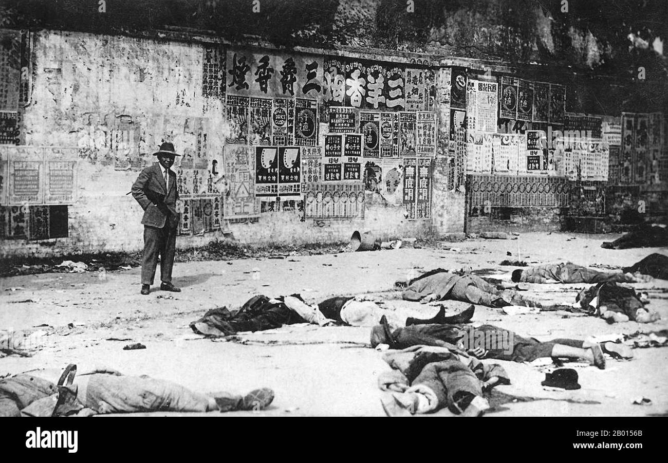 China: Untersuchung der Ergebnisse des „Weißen Terrors“, Shanghai, 12. April 1927. Am 12. April 1927 initiierten Chiang Ka-shek und seine Verbündeten der Grünen Bande eine Säuberung der Kommunisten aus der Kuomintang in Shanghai und begannen umfangreiche Morde. Chiang's Truppen drehten Maschinengewehre auf 100,000 Arbeiter, die bei Gewerkschaftsdemonstrationen auf die Straße gegangen waren, und töteten mehr als 5,000 Menschen. Im April 1927 wurden in Shanghai mehr als 12,000 Menschen getötet oder verschwunden. Der Mann auf dem Bild, der das Gemetzel vermessung, scheint eine Waffe unter seinem Arm zu tragen, und könnte durchaus ein 'Green Gang'-Mobster gewesen sein. Stockfoto