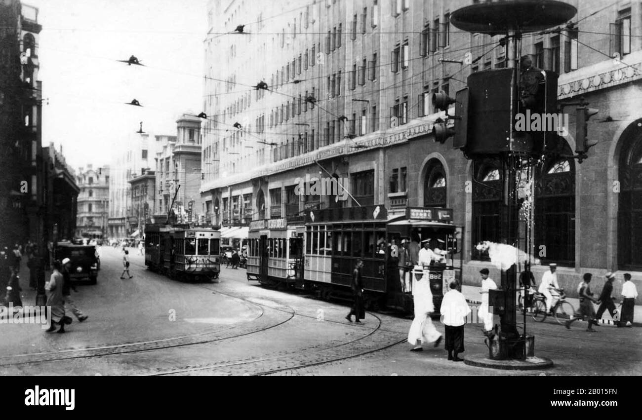 China: Shanghai - Straßenbahnen und Fußgänger auf Nanjing Lu (Nanjing Road) c. 1935. Die Nanjing Road ist die Haupteinkaufsstraße von Shanghai, China, und ist eine der belebtesten Einkaufsstraßen der Welt. Die heutige Nanjing Road besteht aus zwei Abschnitten, der Nanjing Road East und der Nanjing Road West. In einigen Zusammenhängen bezieht sich die „Nanjing Road“ nur auf die Nanjing Road (im Bild) vor 1945, die heutige Nanjing Road East, die heute größtenteils zur Fußgängerzone erklärt wurde. Vor 1949 wurde der englische Name der Straße Nanking Road unter Verwendung der damaligen Standardromanisierung wiedergegeben. Stockfoto