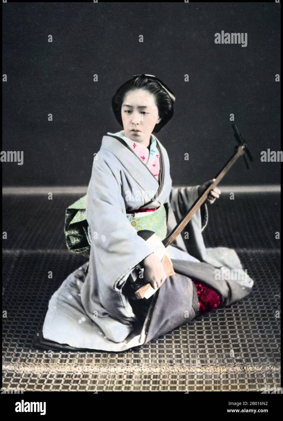 Japan: Eine Geisha spielt eine Shamisen, Tokio, c. 1870er. Geisha, Geiko oder Geigi sind traditionelle japanische Entertainerinnen, die verschiedene japanische Künste wie klassische Musik und Tanz aufführen können. Das Shamisen oder Samisen (wörtlich „drei Geschmacksrichtungen“), auch sangen genannt (wörtlich „drei Streicher“), ist ein dreisaitiges Musikinstrument, das mit einem Plektrum namens Bach gespielt wird. Stockfoto
