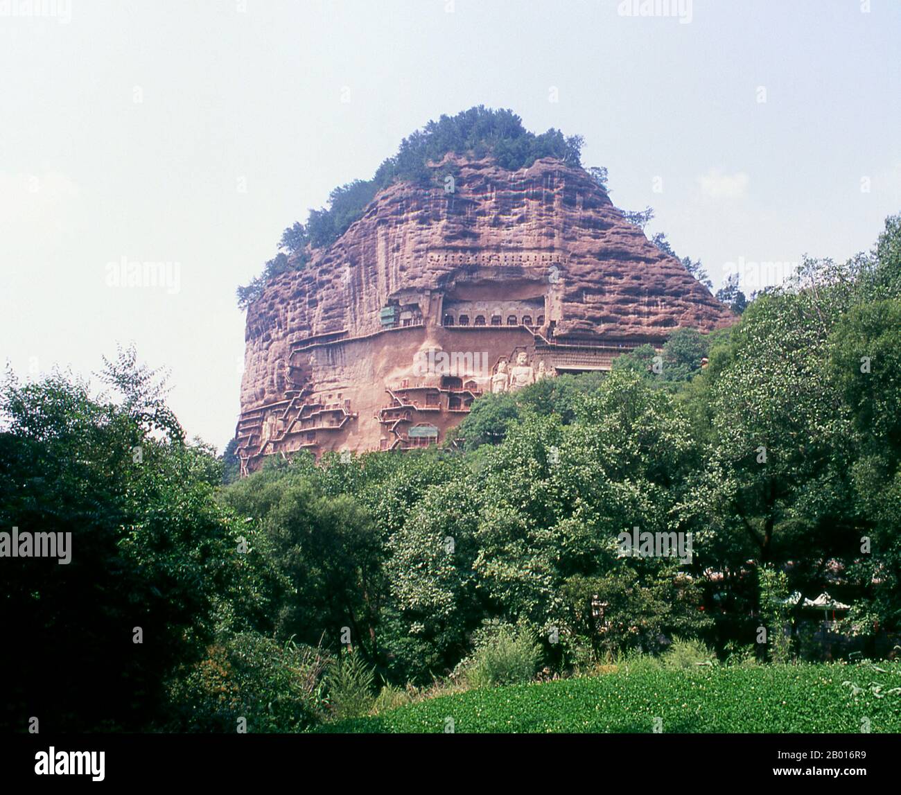 China: Maiji Shan Grotten, Tianshui, Provinz Gansu. Maijishan Shiku (Maiji Shan Grotten) sind eine der vier wichtigsten buddhistischen Tempelgruppen Chinas (die anderen sind Datong, Luoyang und die Mogao-Höhlen in Dunhuang). Ausgehend von den Dynastien Nördlicher Wei (386-535) und Nördlicher Zhou (557-81) schnitten Buddhisten Höhlen in die Seiten eines roten Ausschnitts, der aus den umliegenden Laubhügeln aufsteigt. Figuren des Buddha, von Bodhisattvas und Schülern wurden in härtere Felsen gehauen, die von anderswo hergebracht wurden, und in den Höhlen installiert. Stockfoto