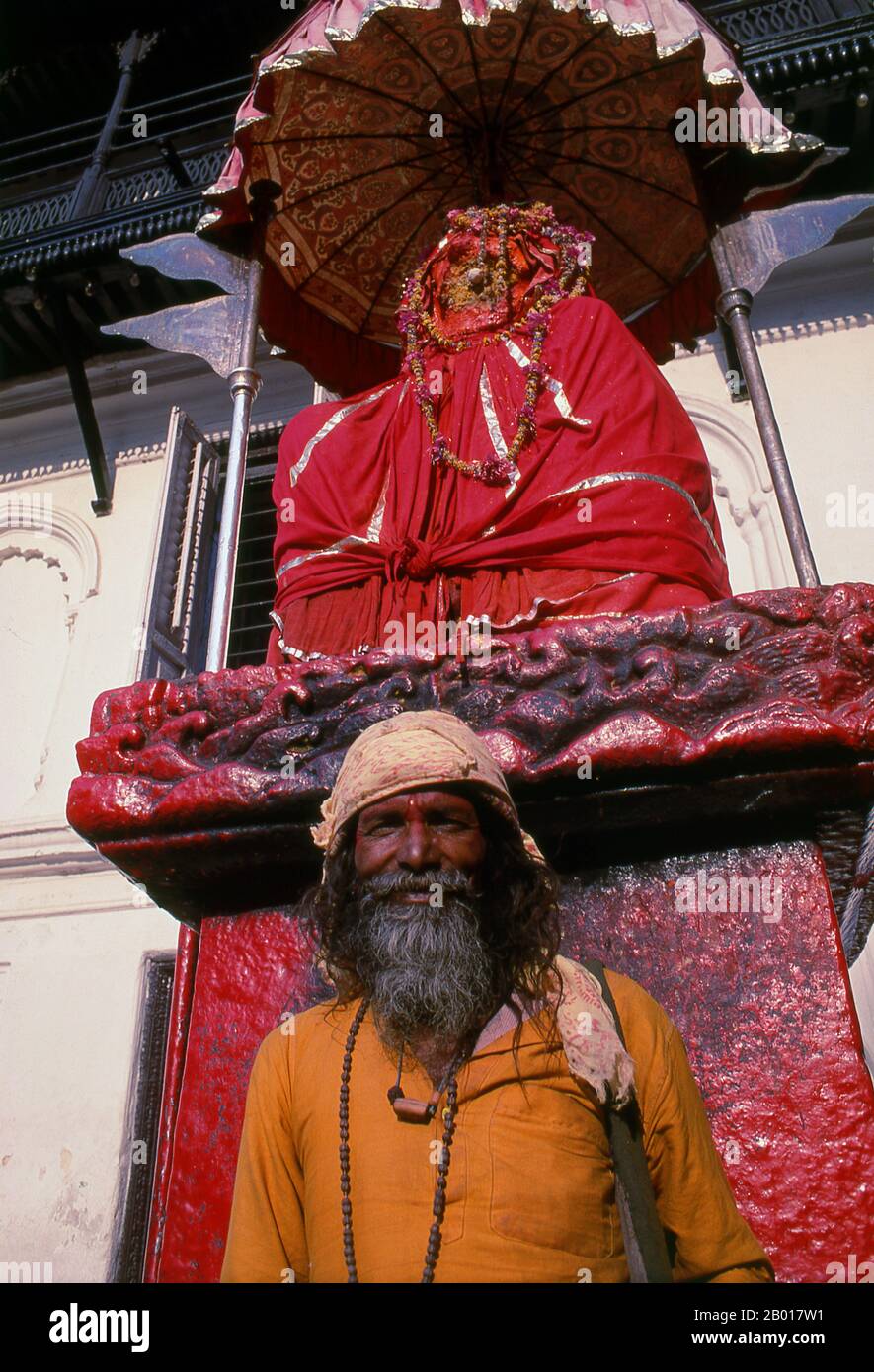 Nepal: Sadhu vor der Hanuman-Statue im Hanuman Dhoka Durbar (Hanuman Royal Palace), Kathmandu. Sie sind, verschiedentlich, als Sadhus (Heilige oder 'gute'), Yogis (asketische Praktizierende) bekannt, Fakiren (asketischer Sucher nach der Wahrheit) und Sannyasine (wandernde Bettelmönchen und Asketen). Sie sind die asketischen – und oft exzentrischen – Praktizierenden einer strengen Form des Hinduismus. Geschworen, irdische Wünsche abzuwerfen, entscheiden sich manche dafür, als Anchoriten in der Wildnis zu leben. Andere sind weniger pensioniert, vor allem in den Städten und Tempeln des nepalesischen Kathmandu-Tals. Stockfoto