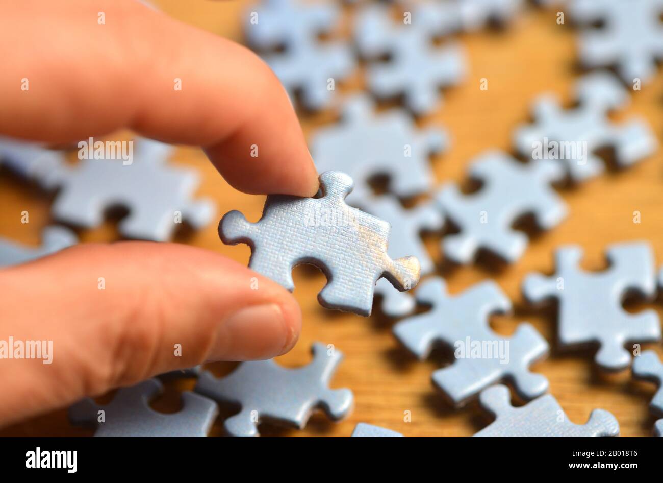Puzzlestück Jigshaw mit einigen Fingern festhalten Stockfoto