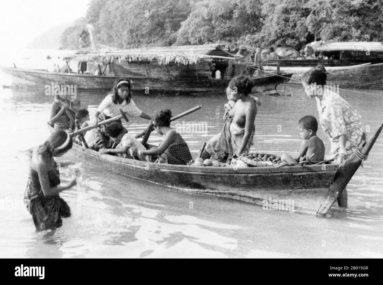 Thailand: Chao Thalae 'Sea Gipsy' Frauen und Kinder mit Booten, Phuket, c. 1960. Die ‘Sea Gypsies’ oder Moken der Andamanensee, im Thailändischen als chao thalae oder ‘People of the Sea’ bekannt, werden in drei Gruppen unterteilt. Sie leben zwischen 4.000 und 5.000 Jahren, sie leben nur an der Küste, entweder in Hütten am Ufer oder auf Booten, die die Küstengewässer vom Mergui-Archipel in Burma bis zu den Tarutao-Inseln im Süden Thailands ausfahren. Die größte Sea Gipsy Gruppe sind die Urak Lawoi, die rund 3.000 zählt. Sie leben in einfachen Hütten an Stränden, die sich südlich von Phuket bis zu den Tarutao-Inseln erstrecken. Stockfoto