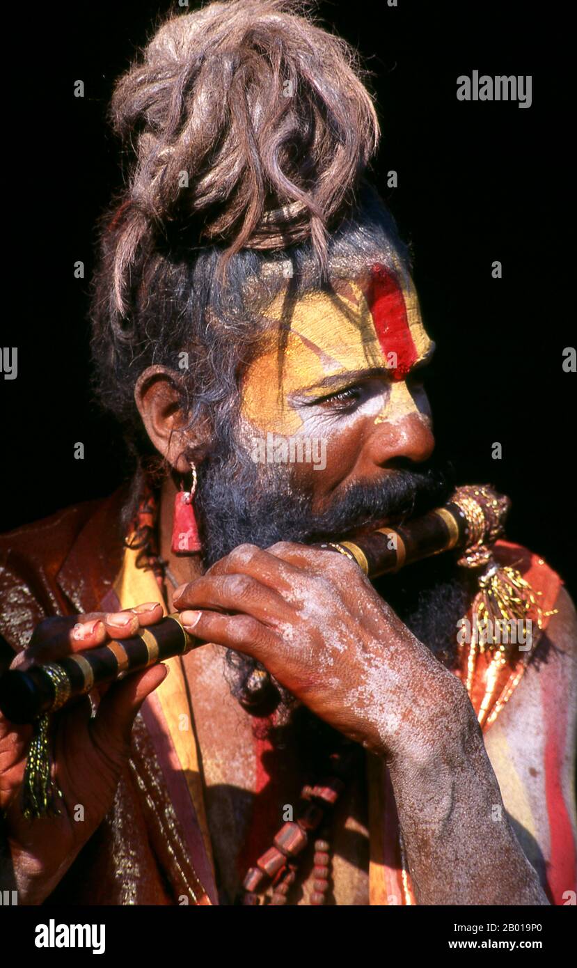 Nepal: Pfeife (Flöte) spielt Sadhu, Pashupatinath, Kathmandu. Sie sind, verschiedentlich, als Sadhus (Heilige oder 'gute'), Yogis (asketische Praktizierende) bekannt, Fakiren (asketischer Sucher nach der Wahrheit) und Sannyasine (wandernde Bettelmönchen und Asketen). Sie sind die asketischen – und oft exzentrischen – Praktizierenden einer strengen Form des Hinduismus. Geschworen, irdische Wünsche abzuwerfen, entscheiden sich manche dafür, als Anchoriten in der Wildnis zu leben. Andere sind weniger pensioniert, vor allem in den Städten und Tempeln des nepalesischen Kathmandu-Tals. Stockfoto