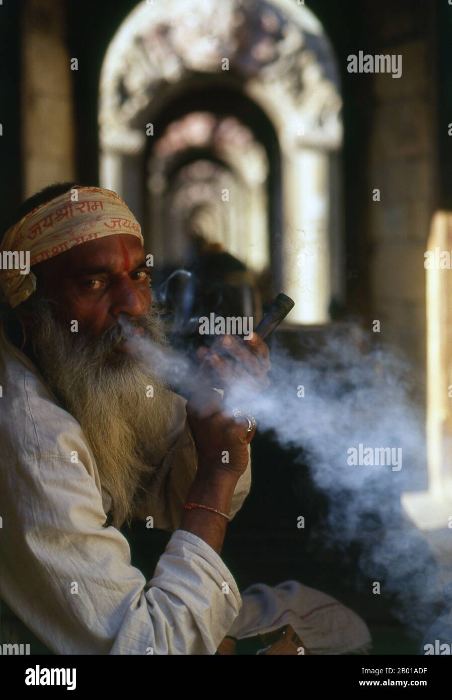 Nepal: Haschisch rauchender Sadhu, Pashupatinath, Kathmandu. Sie sind, verschiedentlich, als Sadhus (Heilige oder 'gute'), Yogis (asketische Praktizierende) bekannt, Fakiren (asketischer Sucher nach der Wahrheit) und Sannyasine (wandernde Bettelmönchen und Asketen). Sie sind die asketischen – und oft exzentrischen – Praktizierenden einer strengen Form des Hinduismus. Geschworen, irdische Wünsche abzuwerfen, entscheiden sich manche dafür, als Anchoriten in der Wildnis zu leben. Andere sind weniger pensioniert, vor allem in den Städten und Tempeln des nepalesischen Kathmandu-Tals. Stockfoto
