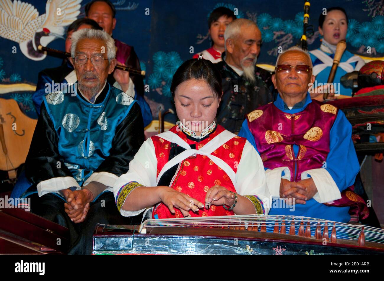 China: Eine Frau pflückt einen Guzheng, das Naxi (Nakhi) Folk Orchestra, die Naxi-Orchesterhalle, die Altstadt von Lijiang, Provinz Yunnan. Naxi-Musik ist 500 Jahre alt und hat mit ihrer Mischung aus literarischen Texten, poetischen Themen und musikalischen Stilen der Tang-, Song- und Yuan-Dynastien sowie einigen tibetischen Einflüssen einen eigenen, einzigartigen Stil und Züge entwickelt. Es gibt drei Hauptstile: Baisha, Dongjing und Huangjing, alle mit traditionellen chinesischen Instrumenten. Die Naxi oder Nakhi sind eine ethnische Gruppe, die am Fuße des Himalaya im Nordwesten der Provinz Yunnan lebt. Stockfoto
