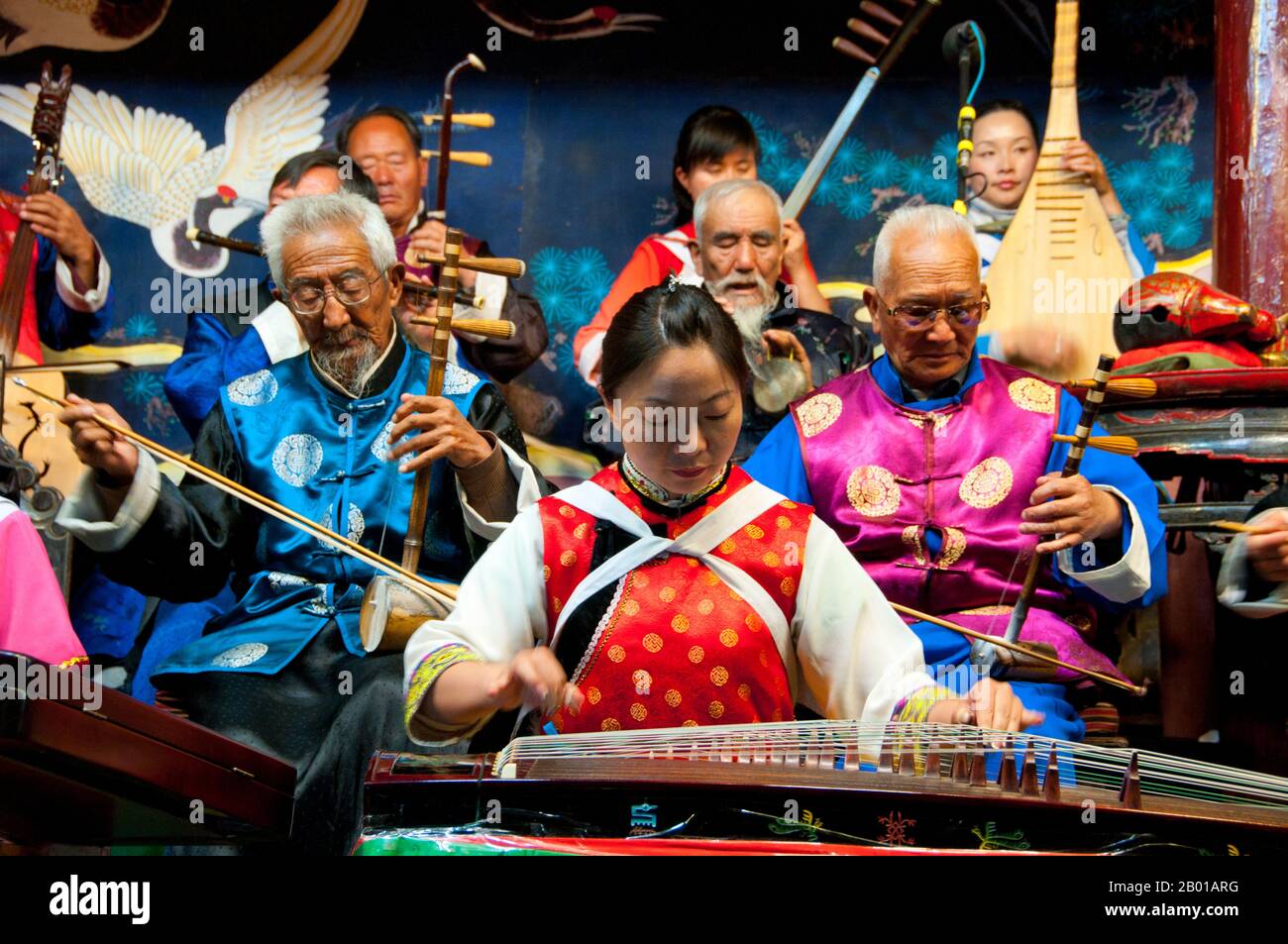 China: Eine Frau pflückt einen Guzheng, das Naxi (Nakhi) Folk Orchestra, die Naxi-Orchesterhalle, die Altstadt von Lijiang, Provinz Yunnan. Naxi-Musik ist 500 Jahre alt und hat mit ihrer Mischung aus literarischen Texten, poetischen Themen und musikalischen Stilen der Tang-, Song- und Yuan-Dynastien sowie einigen tibetischen Einflüssen einen eigenen, einzigartigen Stil und Züge entwickelt. Es gibt drei Hauptstile: Baisha, Dongjing und Huangjing, alle mit traditionellen chinesischen Instrumenten. Die Naxi oder Nakhi sind eine ethnische Gruppe, die am Fuße des Himalaya im Nordwesten der Provinz Yunnan lebt. Stockfoto