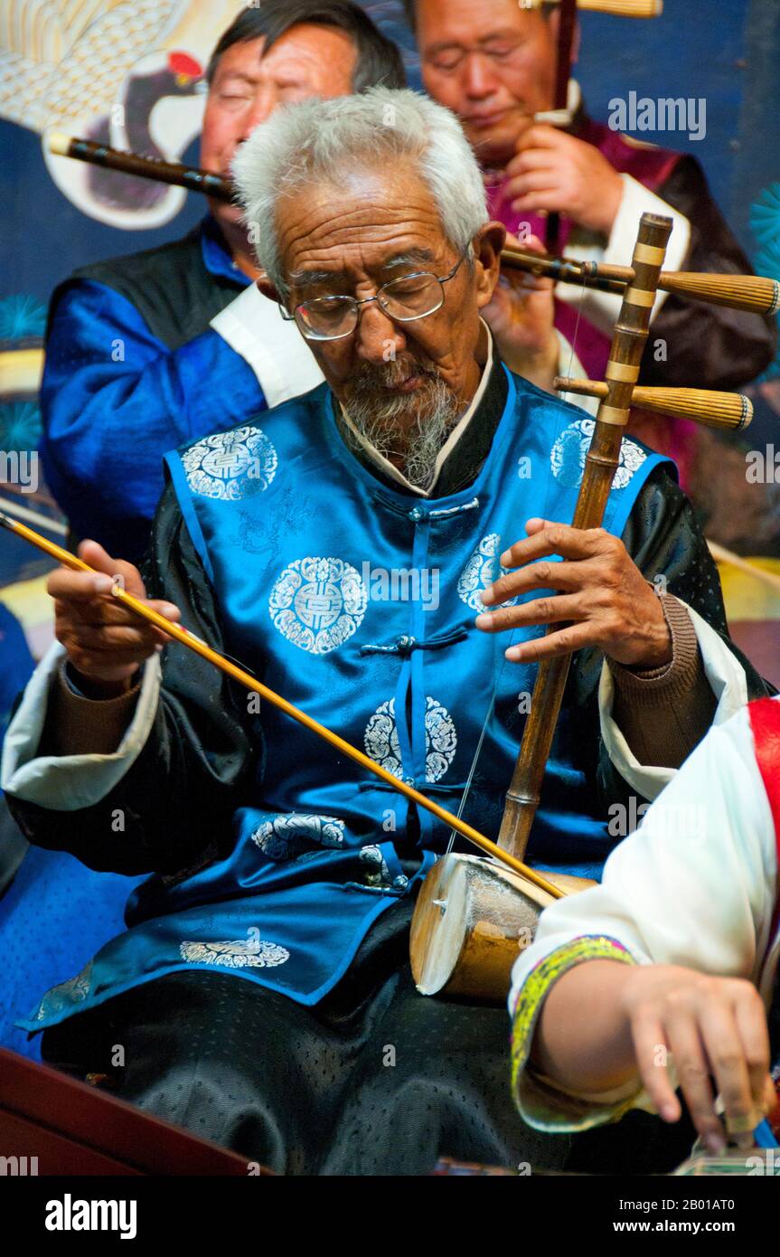 China: Ein Mann spielt einen Erhu, das Naxi (Nakhi) Folk Orchestra, die Naxi Orchestra Hall, Lijiang Old Town, Provinz Yunnan. Naxi-Musik ist 500 Jahre alt und hat mit ihrer Mischung aus literarischen Texten, poetischen Themen und musikalischen Stilen der Tang-, Song- und Yuan-Dynastien sowie einigen tibetischen Einflüssen einen eigenen, einzigartigen Stil und Züge entwickelt. Es gibt drei Hauptstile: Baisha, Dongjing und Huangjing, alle mit traditionellen chinesischen Instrumenten. Die Naxi oder Nakhi sind eine ethnische Gruppe, die am Fuße des Himalaya im Nordwesten der Provinz Yunnan lebt. Stockfoto