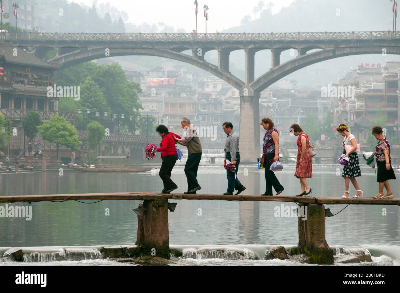 China: Über die alte Holzbrücke über den Tuo-Fluss, Fenghuang, Provinz Hunan. Fenghuang ist Chinesisch für Phoenix und bezieht sich auf den mythischen heiligen feuervogel, der in den Mythologien der Peter, Griechen, Römer, Ägypter, Chinesen, Und (nach Sanchuniathon) die Phönizier. Die Legende besagt, dass zwei Phönixe, die die Stadt entdeckten, einige Zeit über dem Kopf schwebten, bevor sie widerwillig wegflogen. Die Stadt Fenghuang ist eine gut erhaltene antike Stadt, die angeblich aus dem Jahr 248 v. Chr. stammt. Hier leben die Minderheiten Miao und Tujia. Stockfoto