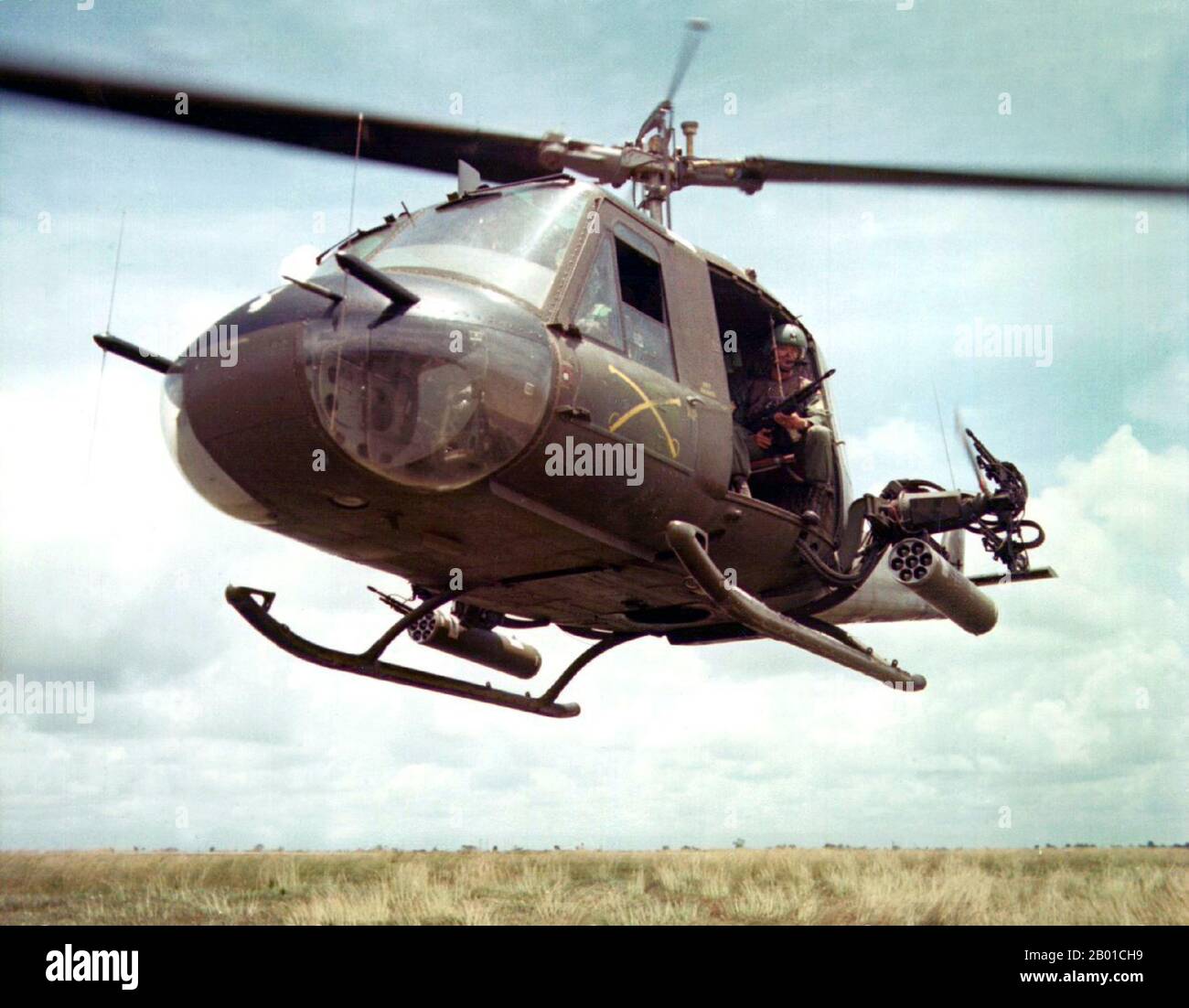 Vietnam: USA Army Sgt. Dennis Troxel sitzt als „Shotgun Rider“ an der Tür eines Hubschraubers der Bell UH-1B Huey der 179. Aviation Company, Vietnam, 1965. Der zweite Indochina-Krieg, in Amerika als Vietnamkrieg bekannt, war ein militärischer Konflikt aus der Zeit des Kalten Krieges, der sich in Vietnam, Laos und Kambodscha vom 1. November 1955 bis zum Fall Saigons am 30. April 1975 ereignete. Dieser Krieg folgte dem ersten Indochina-Krieg und wurde zwischen Nordvietnam, unterstützt von seinen kommunistischen Verbündeten, und der Regierung von Südvietnam, unterstützt von den USA und anderen antikommunistischen Nationen, geführt. Stockfoto