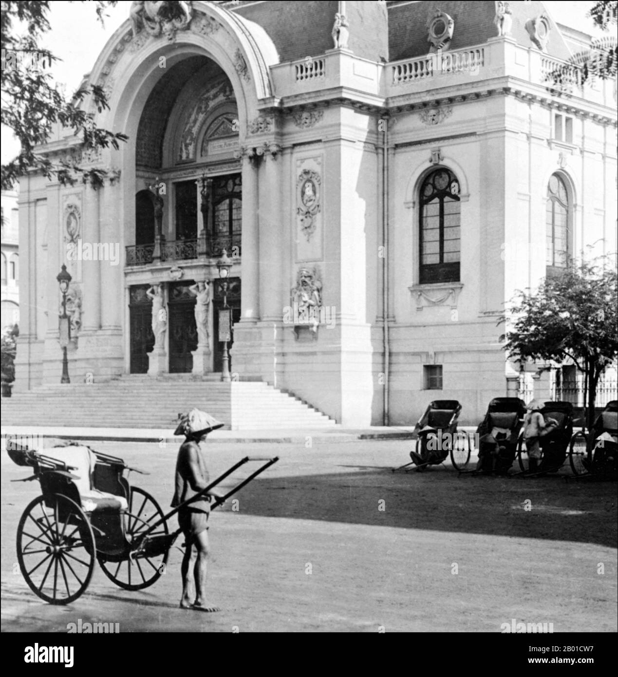 Vietnam: Rikscha vor dem Beaux-Arts Municipal Theatre, auch Saigon Opera House genannt, Saigon, 1915. Das Saigon Opera House (vietnamesisch: Thành phố Hồ Chí Minh), ein Opernhaus in Ho-Chi-Minh-Stadt, Vietnam, ist ein Beispiel für die französische Kolonialarchitektur in Vietnam. Das 1897 vom französischen Architekten Ferret Eugene erbaute Gebäude mit 800 Sitzplätzen wurde nach 1956 als Sitz der Unterhausversammlung von Südvietnam genutzt. Erst 1975 wurde es wieder als Theater genutzt und 1995 restauriert. Stockfoto