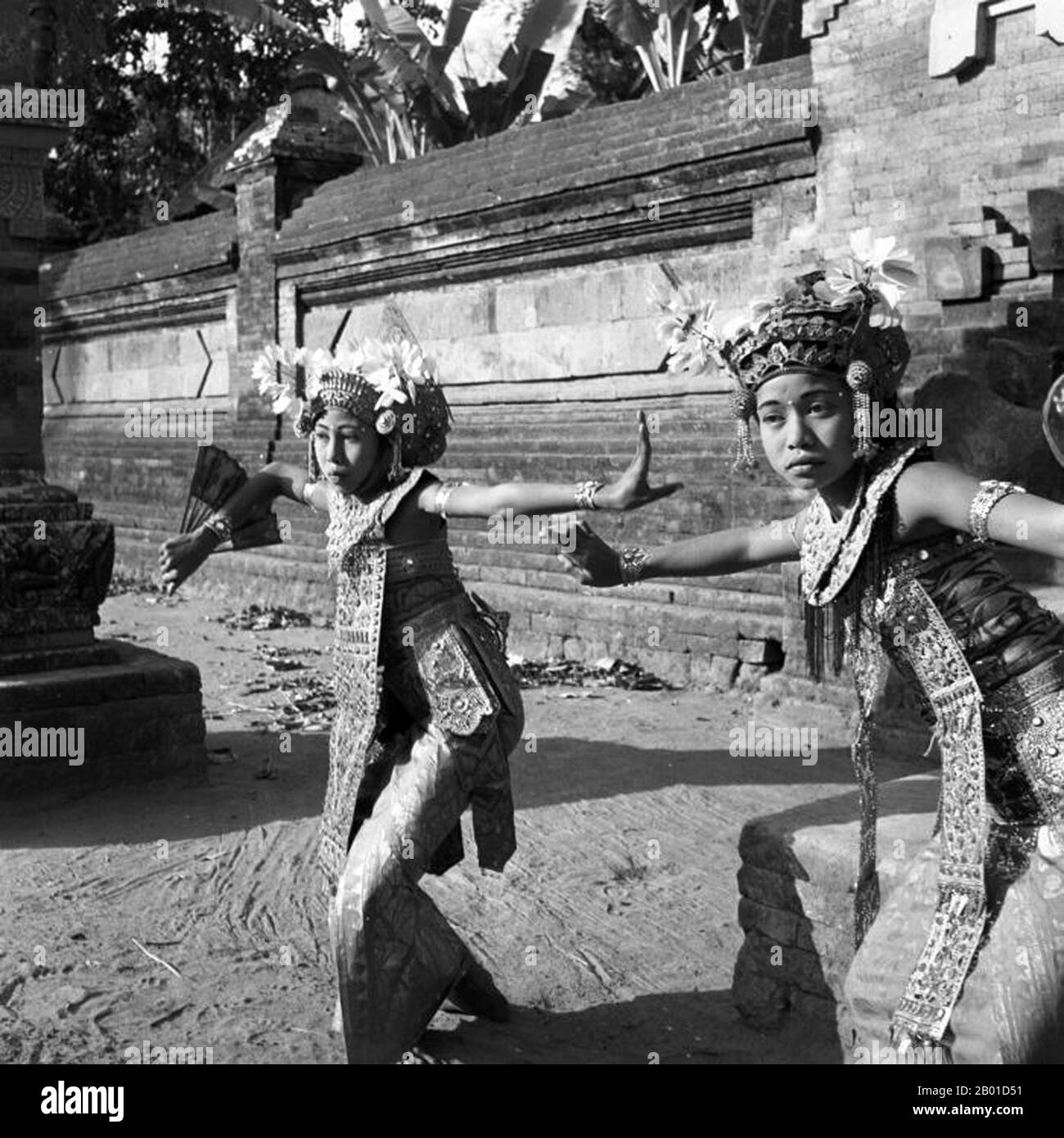 Indonesien: Zwei Legong-Tänzer an einem Tempel auf der Insel Bali, c. 1953. Foto von Paul Spies/Tropenmuseum (CC BY-SA 3,0 Lizenz). Legong ist eine Form des balinesischen Tanzes. Es ist eine raffinierte Tanzform, die sich durch komplizierte Fingerbewegungen, komplizierte Fußarbeit und ausdrucksstarke Gesten und Mimik auszeichnet. Legong entstand wahrscheinlich im 19.. Jahrhundert als königliche Unterhaltung. Der Legende nach wurde ein Prinz von Sukwati krank und hatte einen lebendigen Traum, in dem zwei Mädchen zu Gamelan-Musik tanzten. Als er sich erholte, arrangierte er, dass solche Tänze in Wirklichkeit aufgeführt werden. Stockfoto