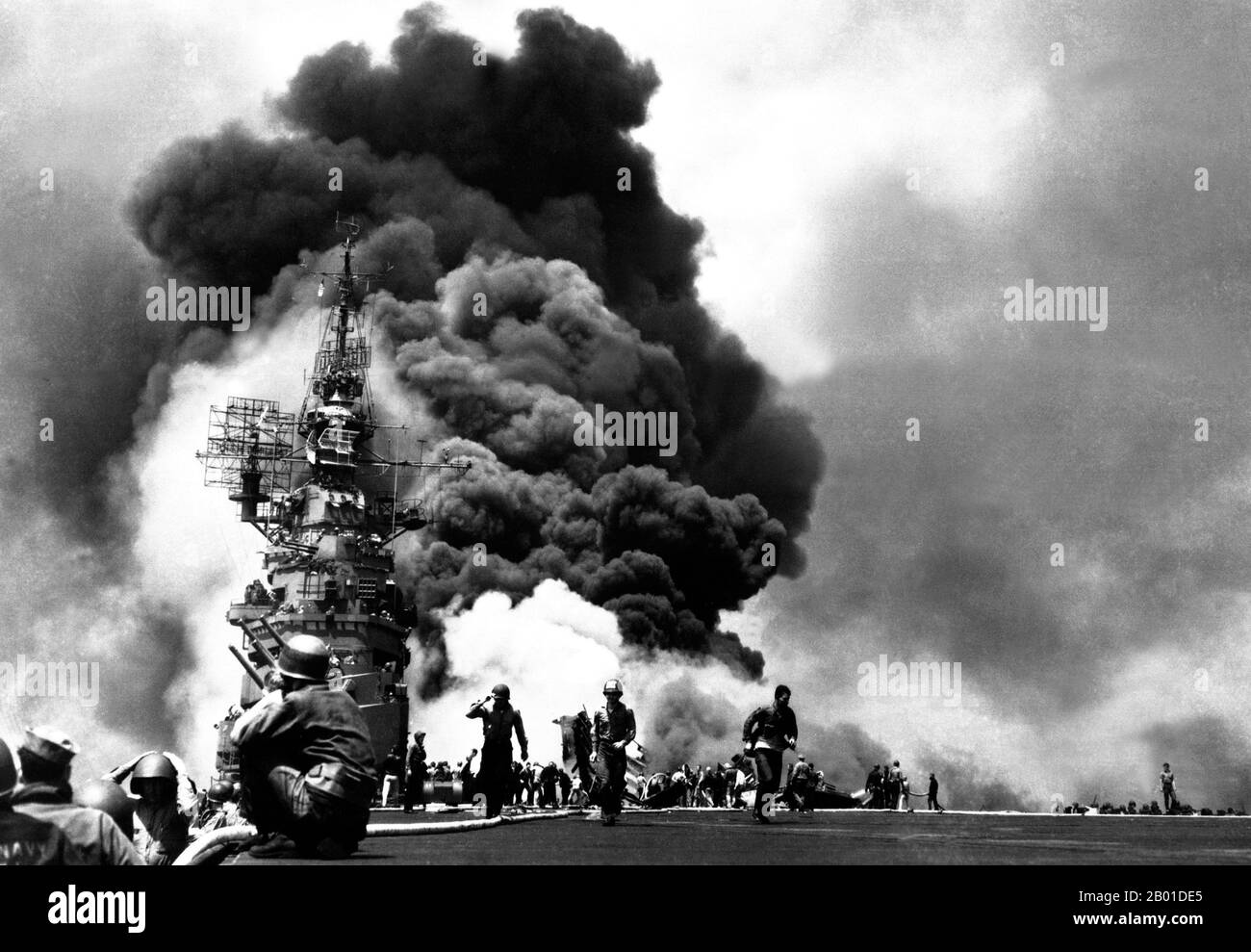 USA/Japan: USS Bunker Hill, getroffen von zwei japanischen Kamikaze-Flugzeugen vor Kyushu, 11. Mai 1945. Kamikaze ("Göttlicher Wind") waren Selbstmordattentate von Militärfliegern aus dem Reich Japan gegen alliierte Marineschiffe in der Endphase der Pazifikkampagne des Zweiten Weltkriegs, die darauf abzielten, so viele Kriegsschiffe wie möglich zu zerstören. Kamikaze-Piloten würden versuchen, ihre Flugzeuge in Flugzeugen mit Sprengstoff, Bomben, Torpedos und vollen Treibstofftanks auf feindliche Schiffe zu stürzen. Die normalen Funktionen des Flugzeugs (Torpedos oder Bomben zu liefern oder andere Flugzeuge abzuschießen) wurden beiseite gelegt. Stockfoto