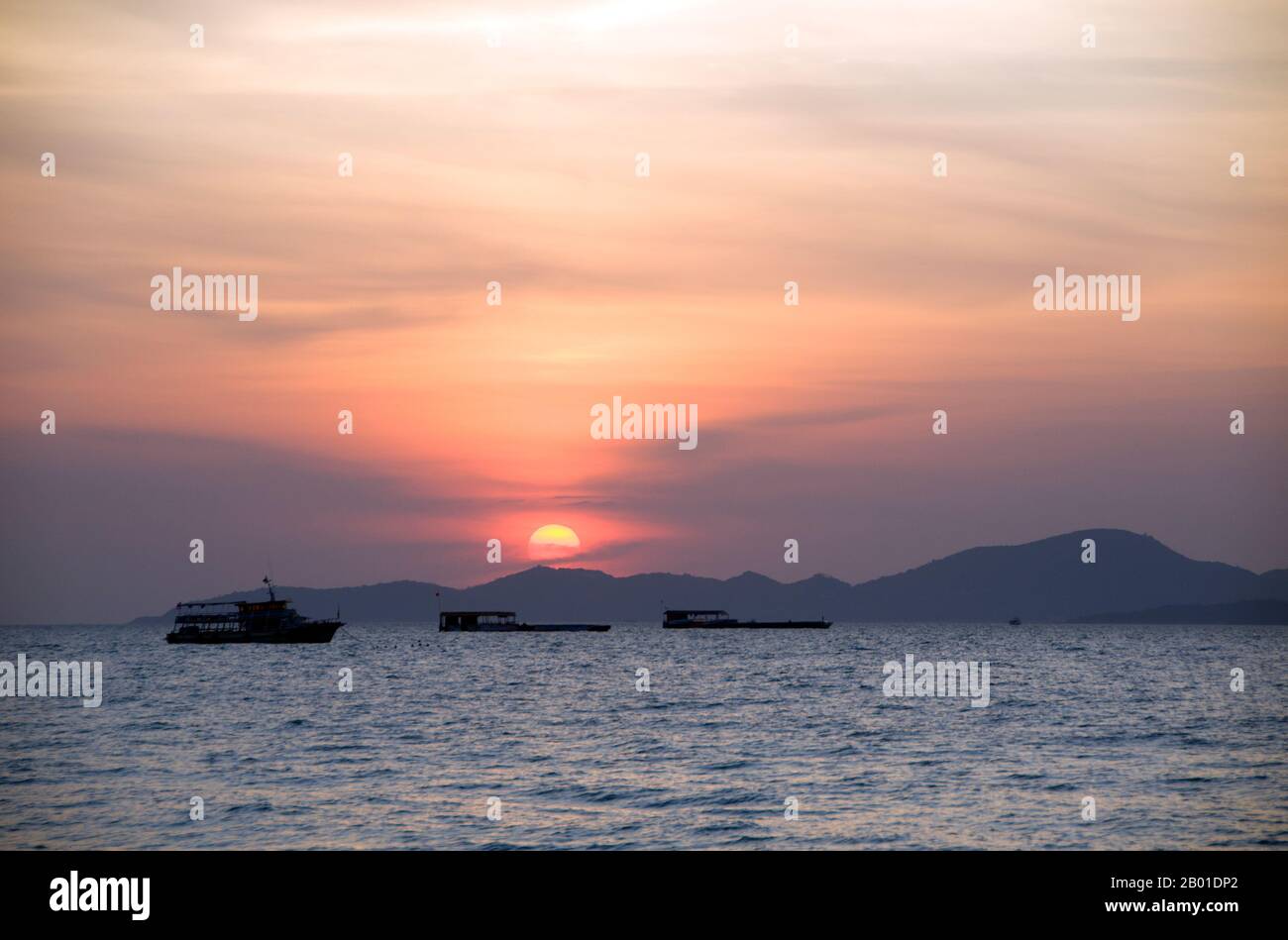 Thailand: Blick in Richtung Ko Larn bei Sonnenuntergang von Pattaya, Provinz Chonburi. Ko Larn liegt 7 km (4,5 Meilen) vor der Küste von Pattaya und ist nur 4km km lang und 2 km breit. Der Haupthafen ist Naban Pier. Es gibt sechs Strände auf der Insel - alles malerische kleine Buchten, die über eine Betonstraße mit dem Naban Pier verbunden sind. Besucher können die Insel mit einem Pick-up-Taxi, einem Motorradtaxi oder einem Motorradverleih erkunden. Jeder Strand hat Gästehäuser, Restaurants, Geschäfte und Touristeneinrichtungen. In der Hauptsaison oder am Wochenende ist die Insel sehr beliebt. Stockfoto