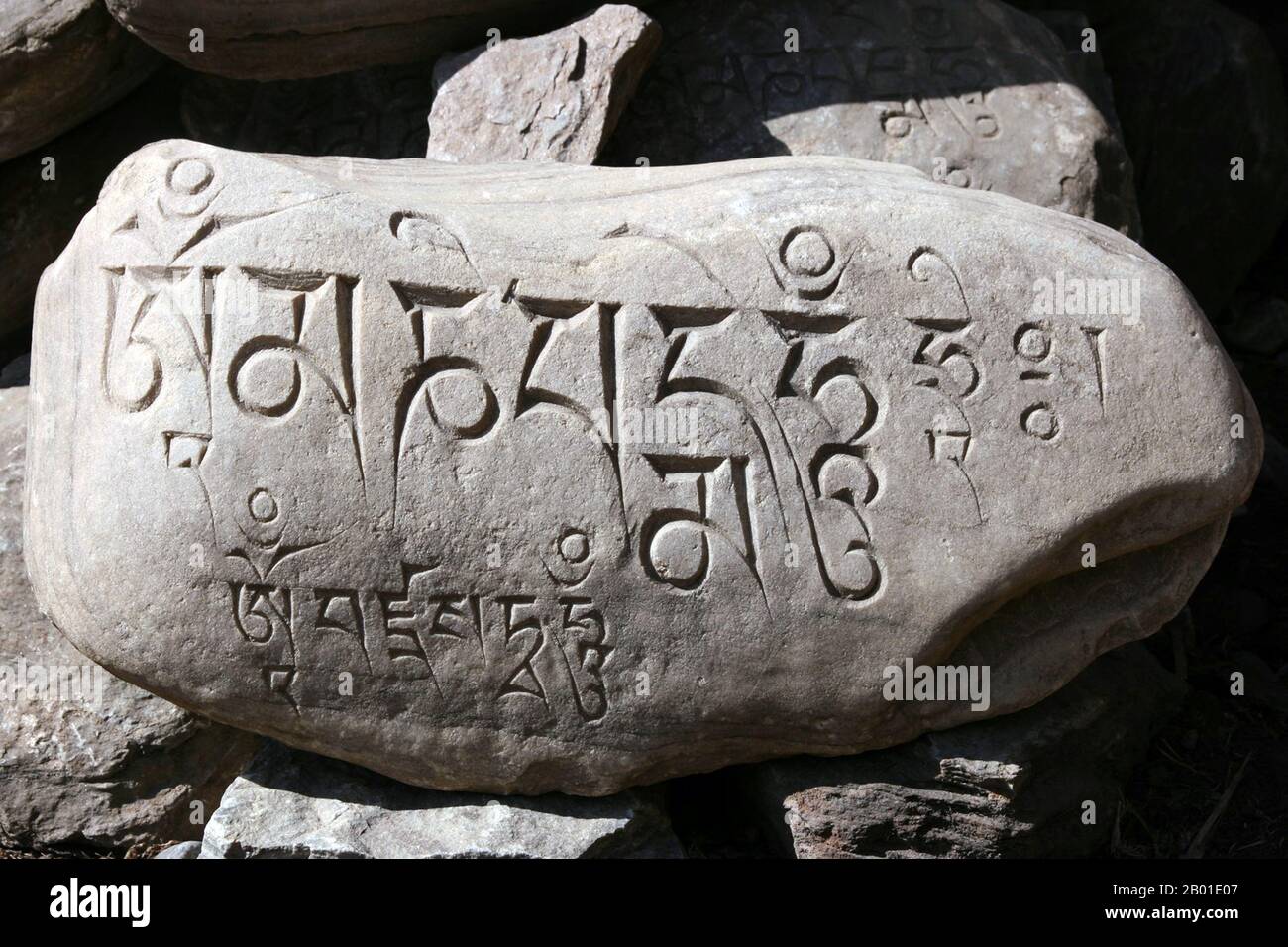 China/Tibet: Ein buddhistischer Mahayana-Mani-Stein mit Mantra in tibetischer Schrift. Foto: Jolly Nomad (CC BY-SA 3,0 Lizenz), 2008. Mani-Steine sind Steinplatten, Steine und/oder Kiesel, die mit dem sechs Silben von Avalokiteshvara (Om mani padme Summ, daher der Name „Mani-Steine“) als Form des Gebets im tibetischen Buddhismus versehen sind. Der Begriff Maniktstein kann auch lose für Steine verwendet werden, auf denen Mantra oder hergebrachte Muster (z. B. Aschtamangala) aufgebracht sind. Maniksteine werden absichtlich entlang der Straßen und Flüsse platziert oder zusammen platziert, um Hügel oder cairns zu bilden. Stockfoto
