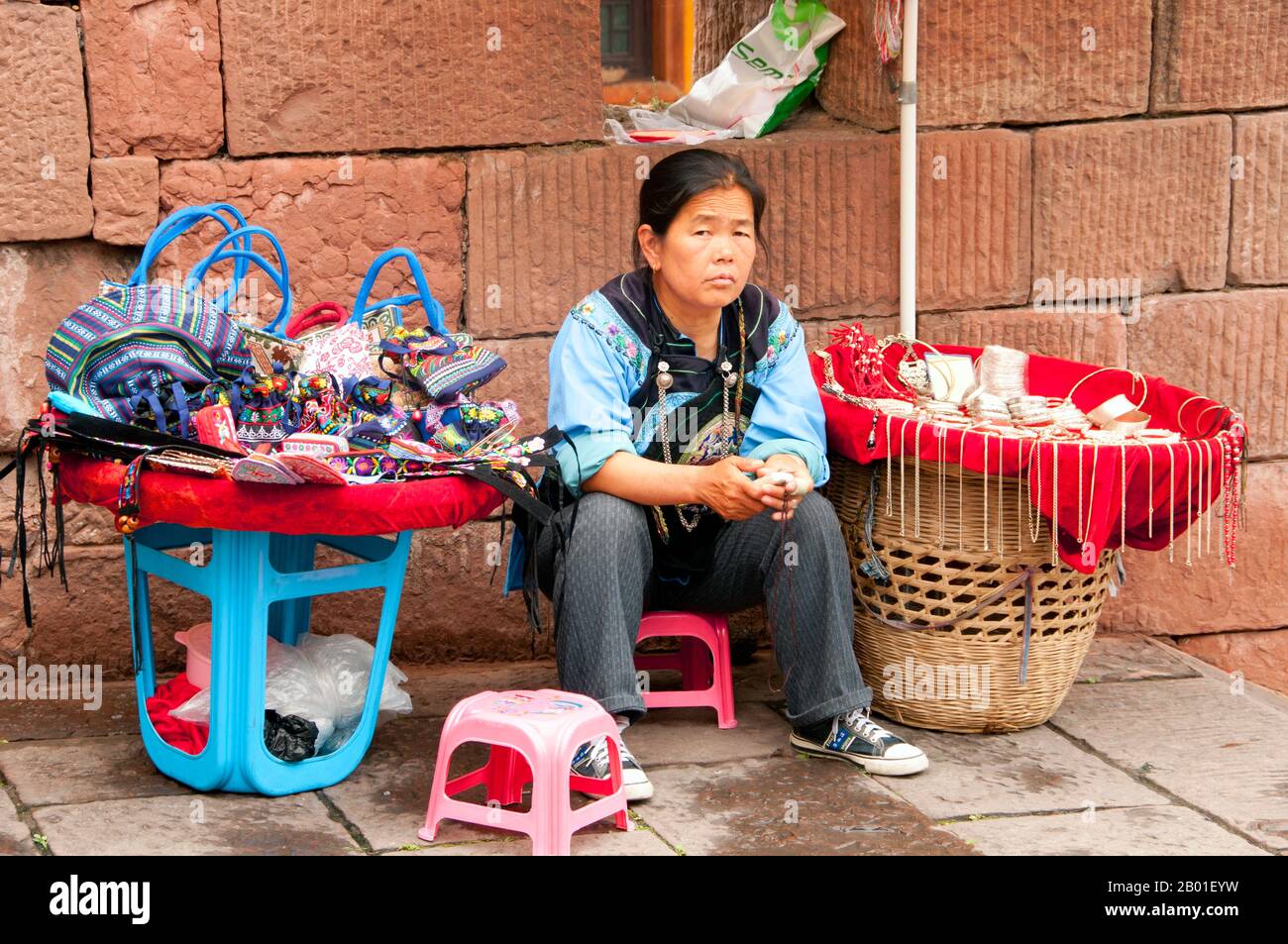 China: Tujia-Frau, die Kunsthandwerk am North Gate Tower, Fenghuang, Provinz Hunan verkauft. Fenghuang ist Chinesisch für Phoenix und bezieht sich auf den mythischen heiligen feuervogel, der in den Mythologien der Perser, Griechen, Römer, Ägypter, Chinesen, Und (laut Sanchuniathon) die Phönizier. Der Legende nach schwebten zwei Phoenixe bei der Entdeckung der Stadt über längere Zeit, bevor sie widerwillig wegflogen. Die Stadt Fenghuang ist eine gut erhaltene antike Stadt, die angeblich aus dem Jahr 248 BCE stammt. Hier leben die Minderheiten Miao und Tujia. Stockfoto