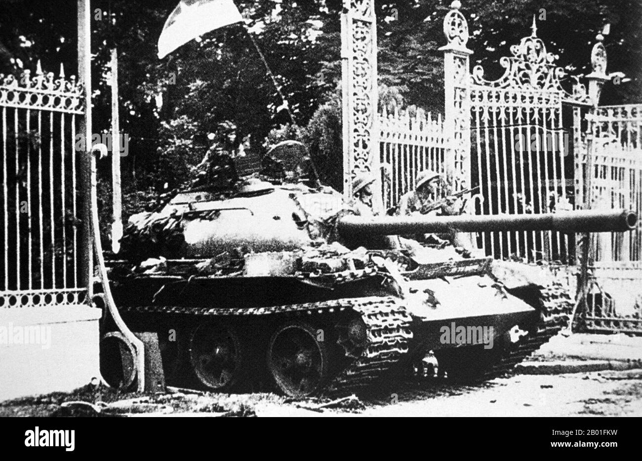Vietnam: Ein kommunistischer Panzer stürzt durch den Umzaun in den Präsidentenpalast, Saigon, April 1975. Foto der Vietnam News Agency (CC BY-SA 3,0 Lizenz). Der zweite Indochina-Krieg, in Amerika als Vietnam-Krieg bekannt, war ein Militärkonflikt aus der Zeit des Kalten Krieges, der sich in Vietnam, Laos und Kambodscha vom 1. November 1955 bis zum Fall Saigons am 30. April 1975 ereignete. Dieser Krieg folgte dem ersten Indochina-Krieg und wurde zwischen Nordvietnam, unterstützt von seinen kommunistischen Verbündeten, und der Regierung Südvietnams, unterstützt von den USA und anderen antikommunistischen Nationen, geführt. Stockfoto