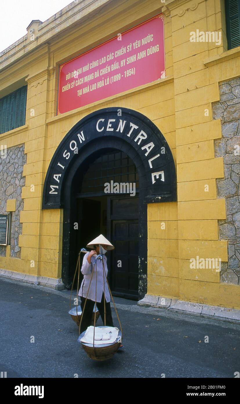 Vietnam: Ein Verkäufer geht vorbei am Eingang zum Hoa Lo Gefängnismuseum (das alte französische Maison Centrale), Hanoi. Die französische Kolonialverwaltung baute 1896 das Hoa Lo Gefängnis. Ursprünglich sollten 450 Gefangene festgehalten werden, und in den 1930er Jahren war die Zahl der Inhaftierten auf fast 2.000 angestiegen, die politische Gefangene mit großer Mehrheit. Das Hoa Lo Gefängnis wurde während des Zweiten Indochina-Krieges als Ort der Inhaftierung für niedergeschlagene US-Piloten bekannt, die das Gefängnis ironischerweise „Hanoi Hilton“ nannten. Stockfoto