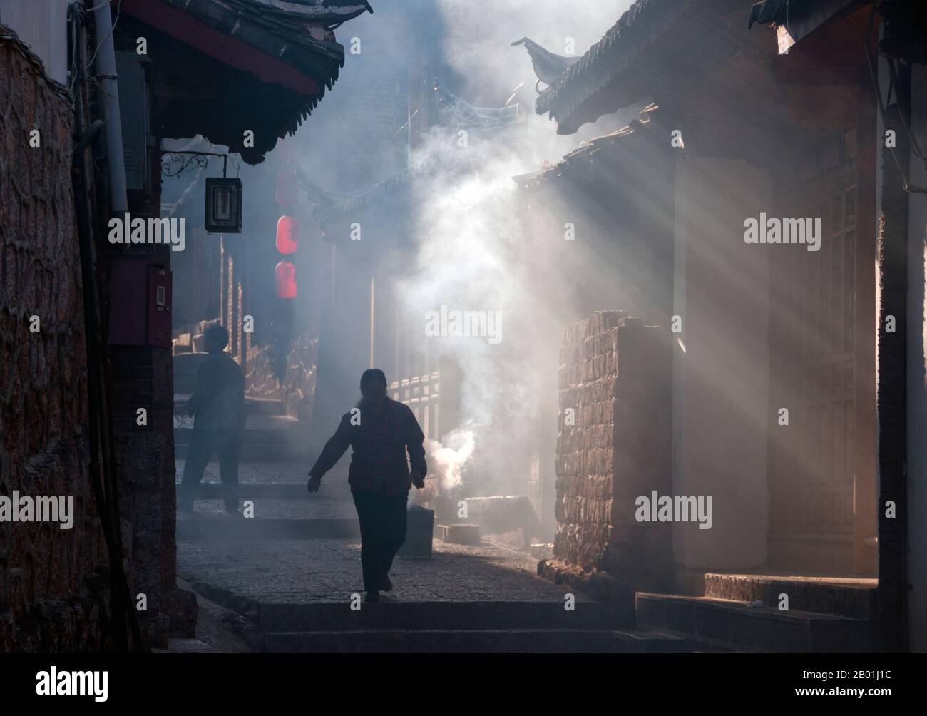 China: Eine rauchige Seitenstraße, Altstadt von Lijiang, Provinz Yunnan. Die Naxi oder Nakhi sind eine ethnische Gruppe, die in den Ausläufern des Himalaya im Nordwesten der Provinz Yunnan und im Südwesten der Provinz Sichuan in China lebt. Man geht davon aus, dass die Naxi ursprünglich aus Tibet stammen und bis vor kurzem die Landhandelsverbindungen mit Lhasa und Indien aufrechterhalten haben. Die Naxi gehören zu den 56 ethnischen Gruppen, die von der Volksrepublik China offiziell anerkannt wurden. Die Naxi sind traditionell Anhänger der Dongba-Religion. Stockfoto